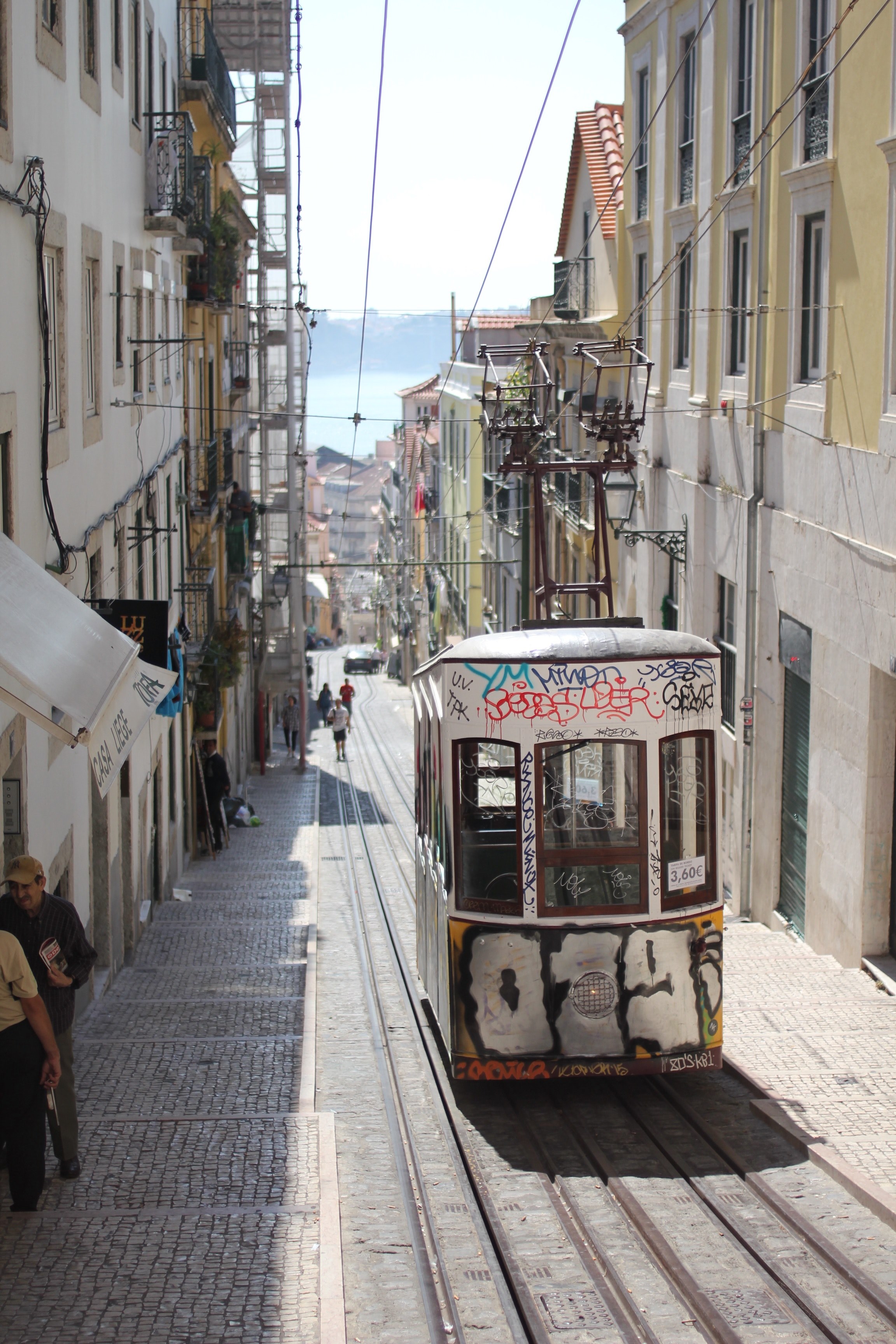abandoned street tram filled with graffiti sitting stationary in a lisbon street as people walk by, tram in lisbon 4k, Phone HD Wallpaper