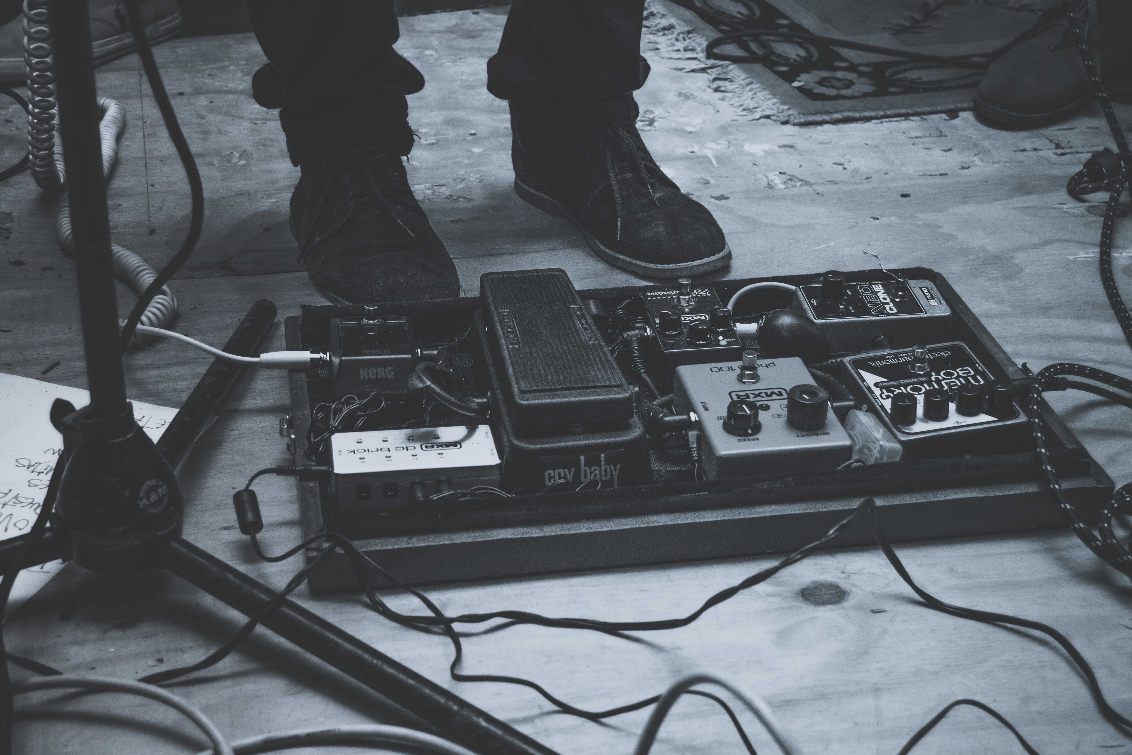 a low black and white shot of music equipment next to a persons shoes on stage, music equipment flat on the stage 4k, HD Wallpaper