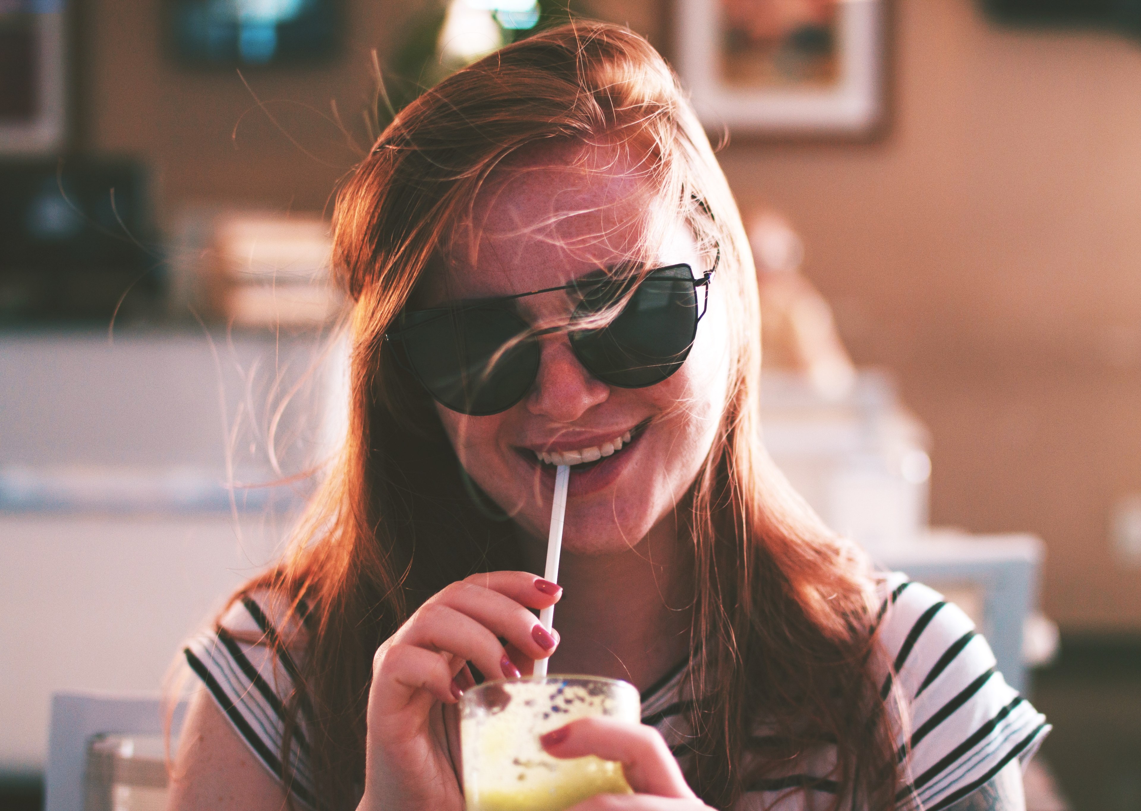a smiling woman with sunglasses and windswept hair drinks from a straw in a natal cafe, babe look at me really fast please 4k, HD Wallpaper