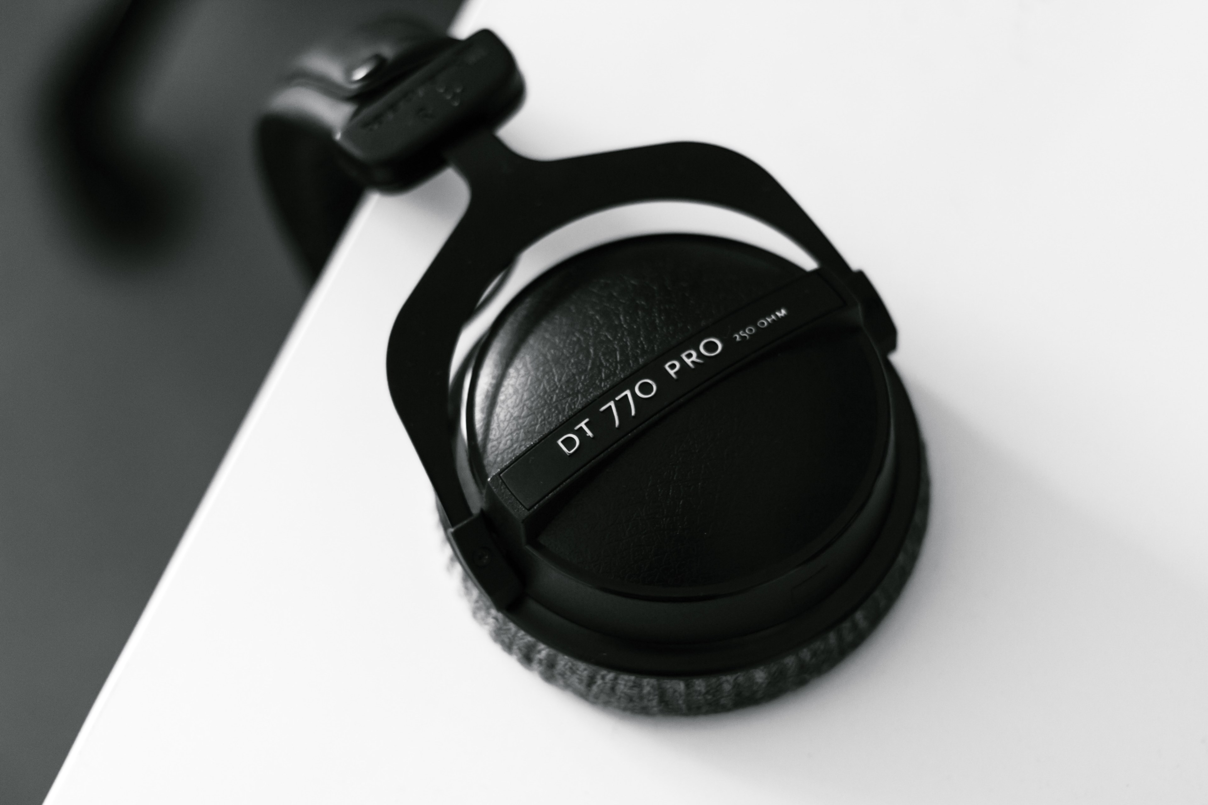 close up of black headphones hanging from a white surface, top view of headphones hanging from a desk 4k, HD Wallpaper