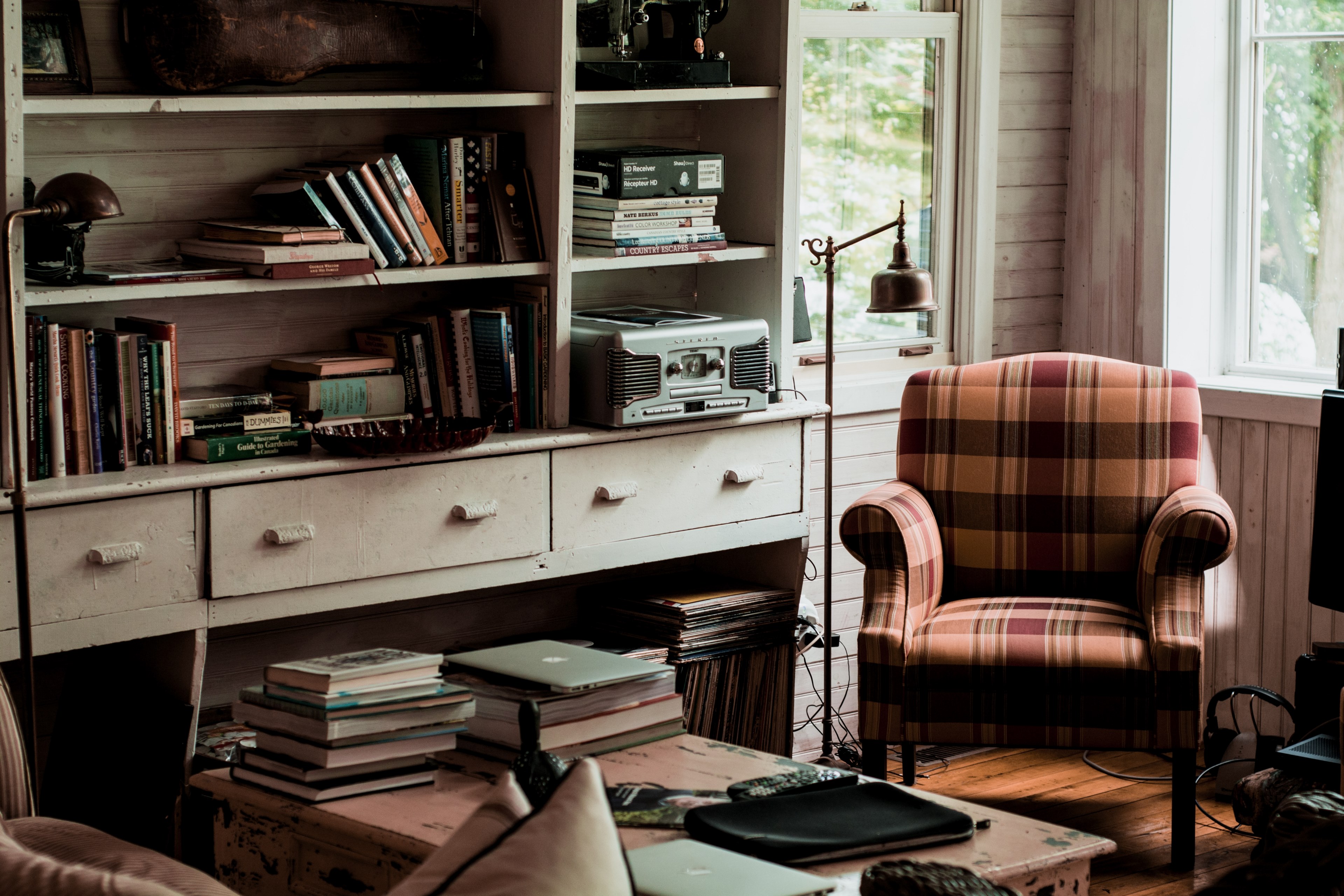 living room interior filled with books on the table and bookshelf with a plaid chair, books in living room 4k, HD Wallpaper