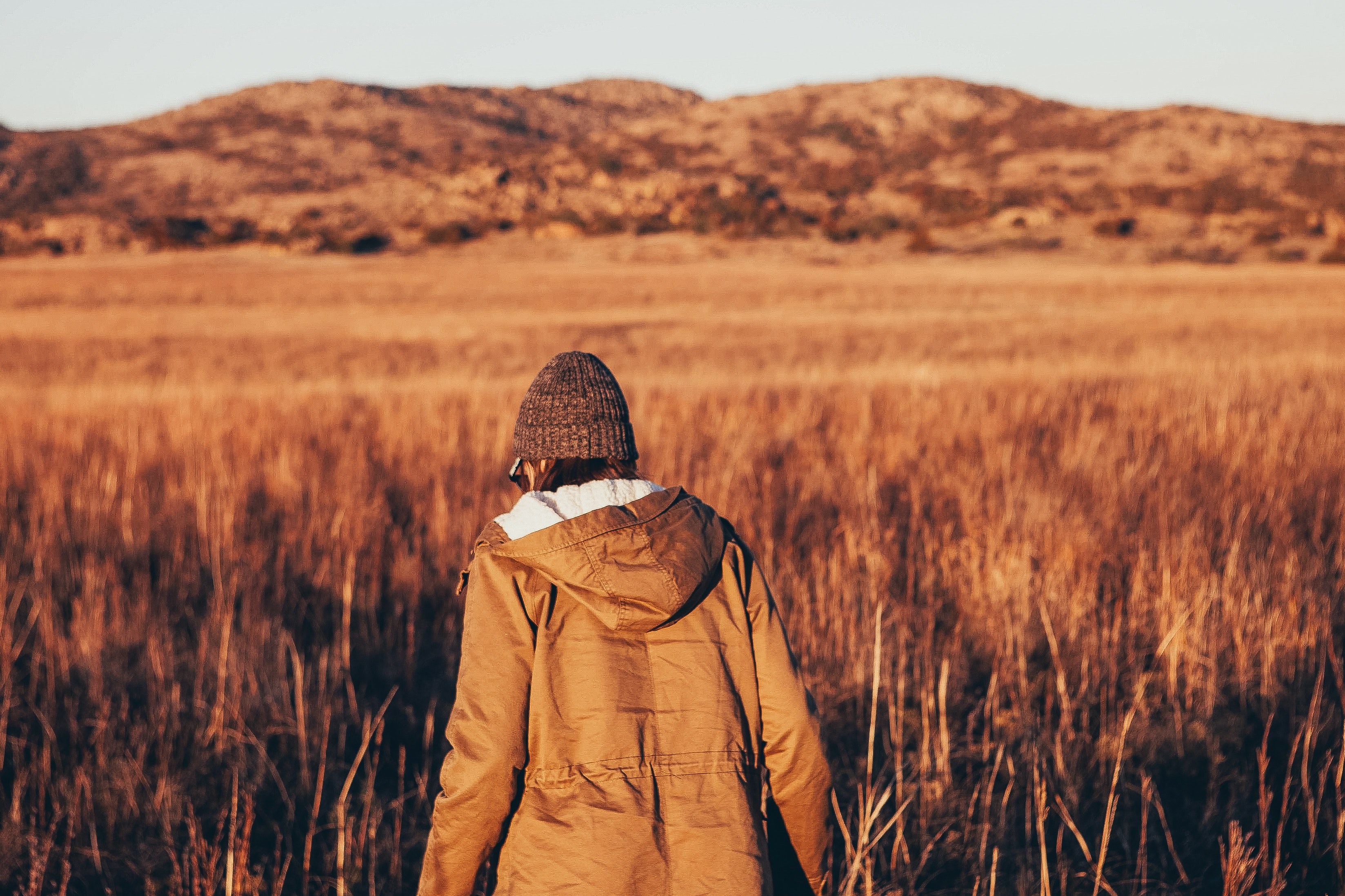 a person in a coat faces away while hiking in a field by the wichita mountains, hiking in witchita mountains 4k, HD Wallpaper