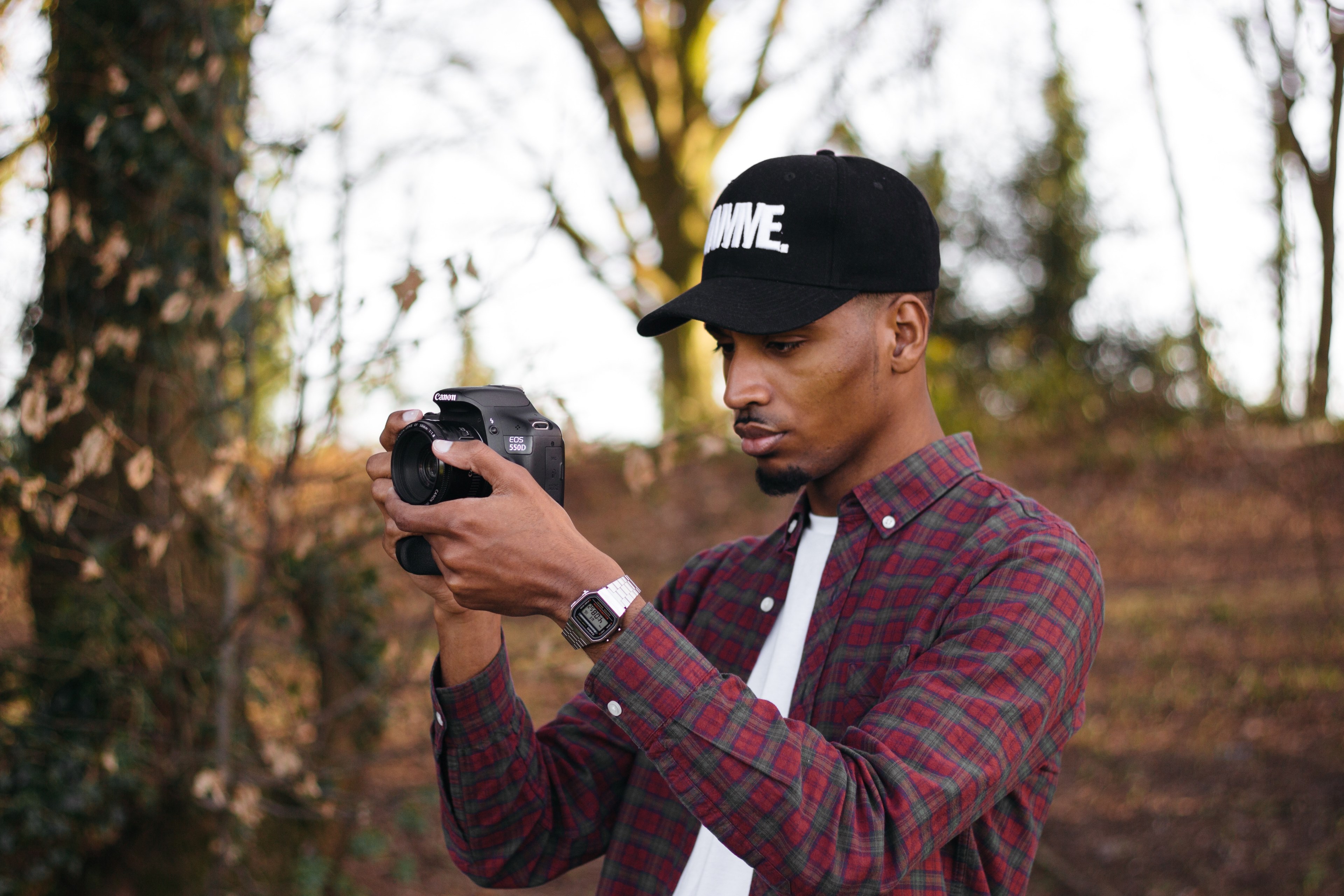 a man in a flannel shirt watch and black baseball cap takes a picture outdoors, man taking picture outdoors 4k, HD Wallpaper