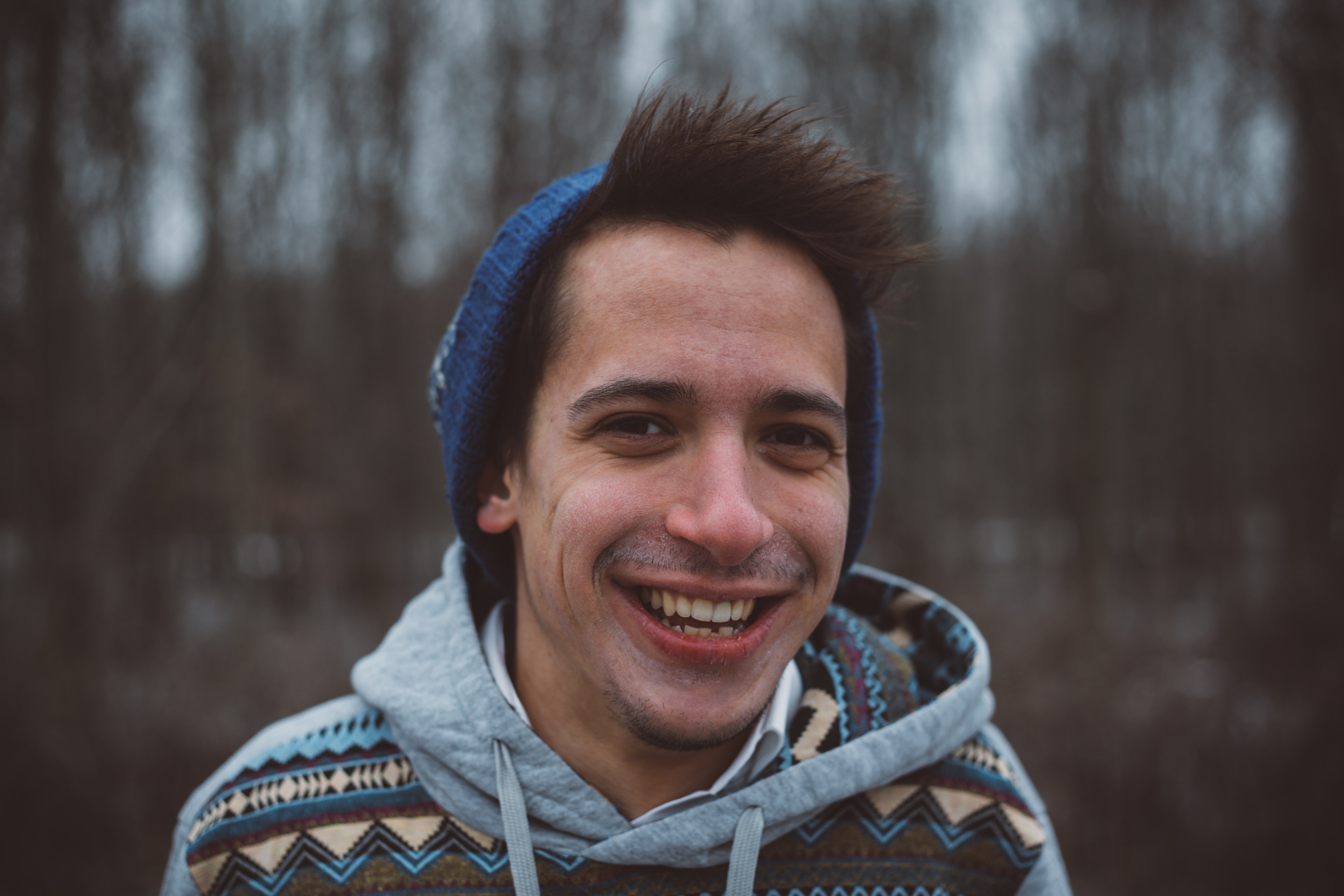 brunette man wearing a hoodie and a hat smiling in a forest in hungary, lost in the wilderness 4k, HD Wallpaper