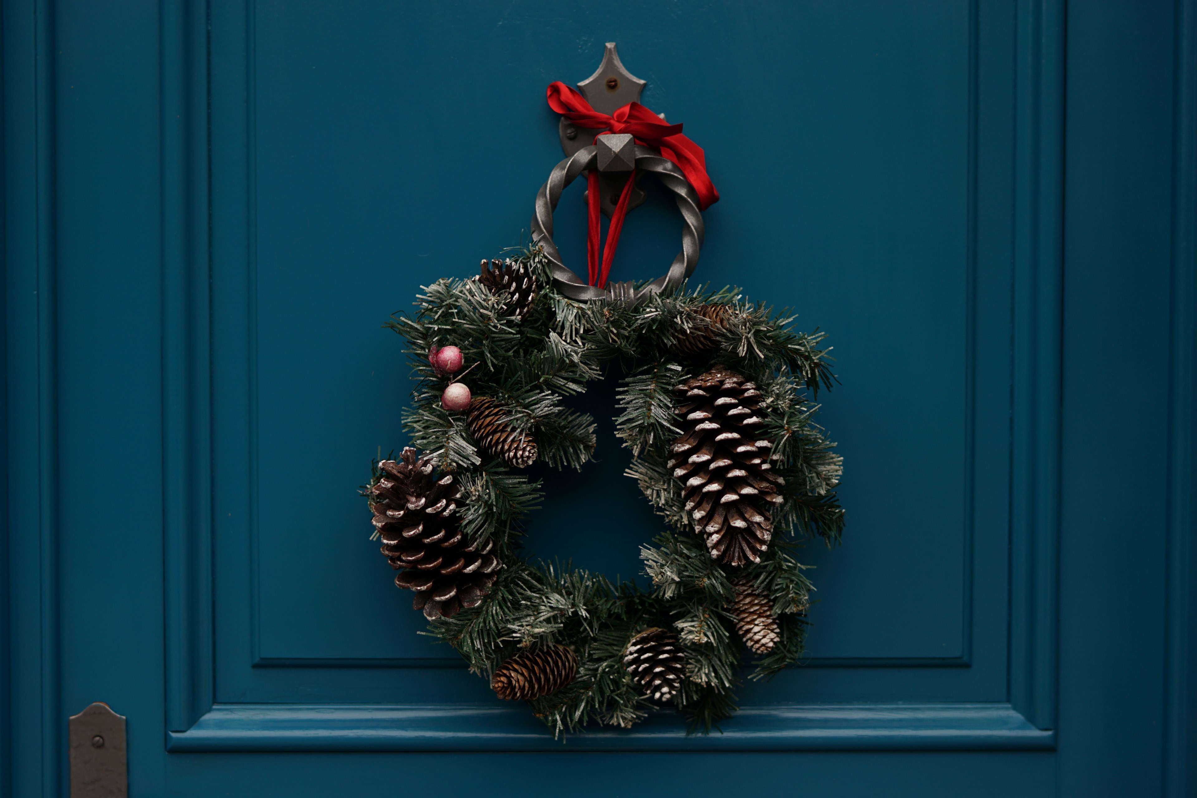 an evergreen wreath decorated with berries and pine cones hangs on a teal door, december means christmas 4k, HD Wallpaper