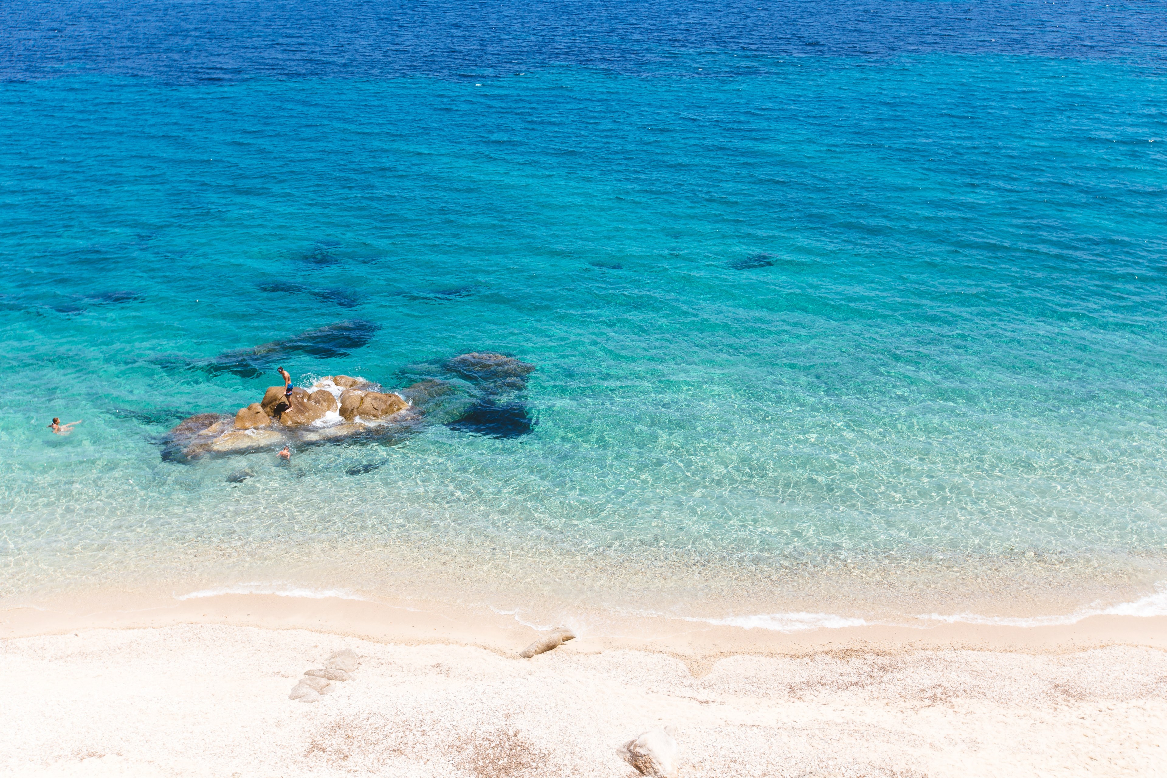 drone view of a person standing on a rock in a clear blue shallow ocean by the fava sand beach, blue ocean by the sand beach 4k, HD Wallpaper