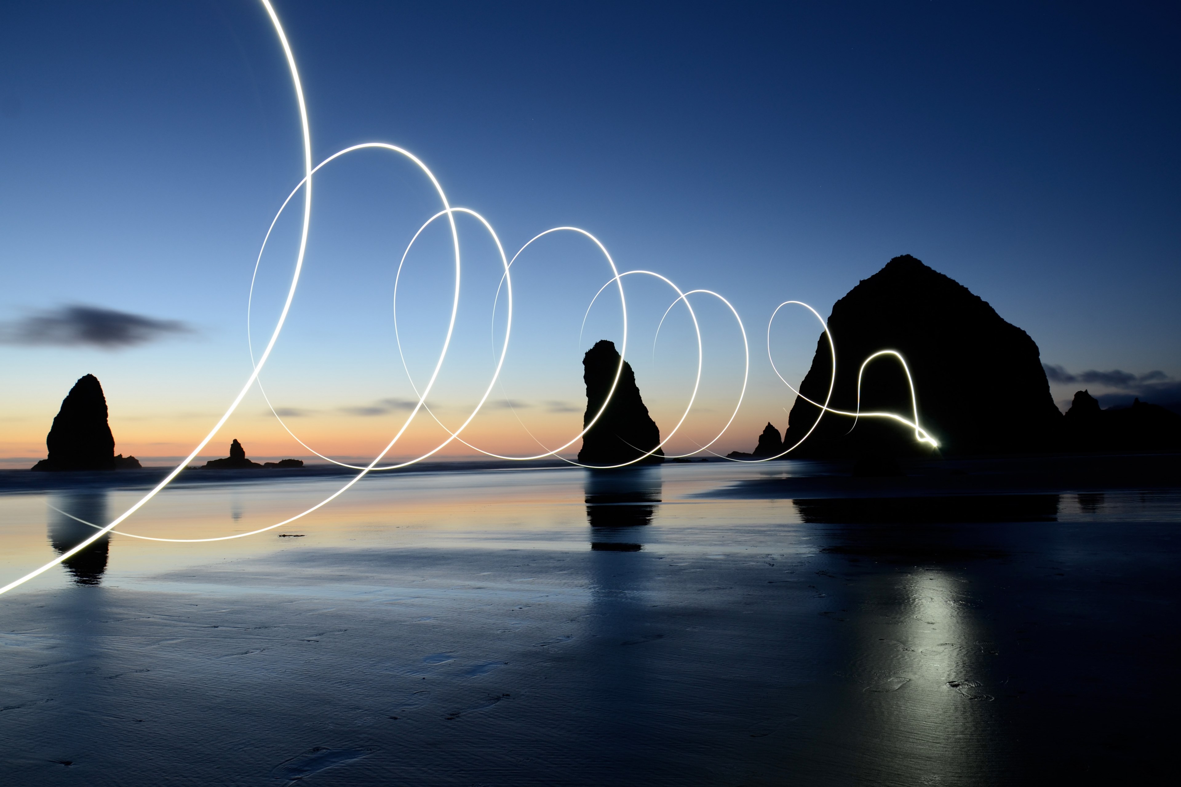 a light painting shot captured with long exposure in cannon beach, light painting spirals over the water 4k, HD Wallpaper