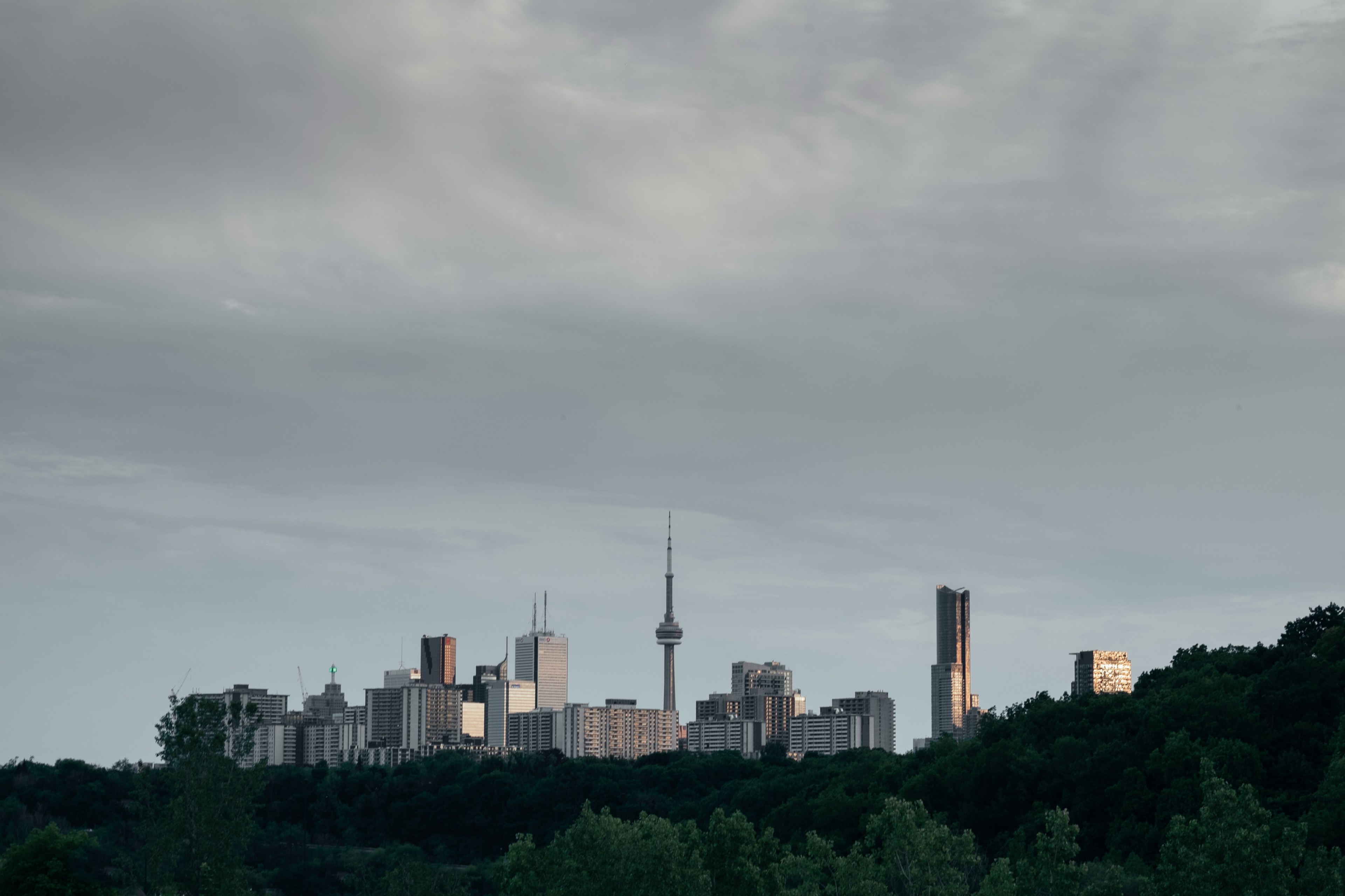 a city skyline with a tall broadcast tower under gray clouds, city under overcast sky 4k, HD Wallpaper