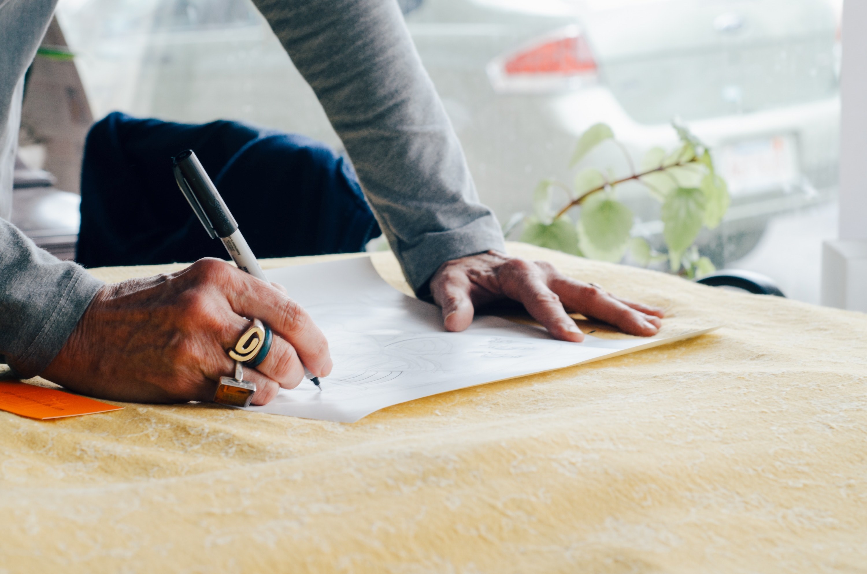 a person leaning over a table and drawing on a piece of paper, designer leaning over table 4k, HD Wallpaper