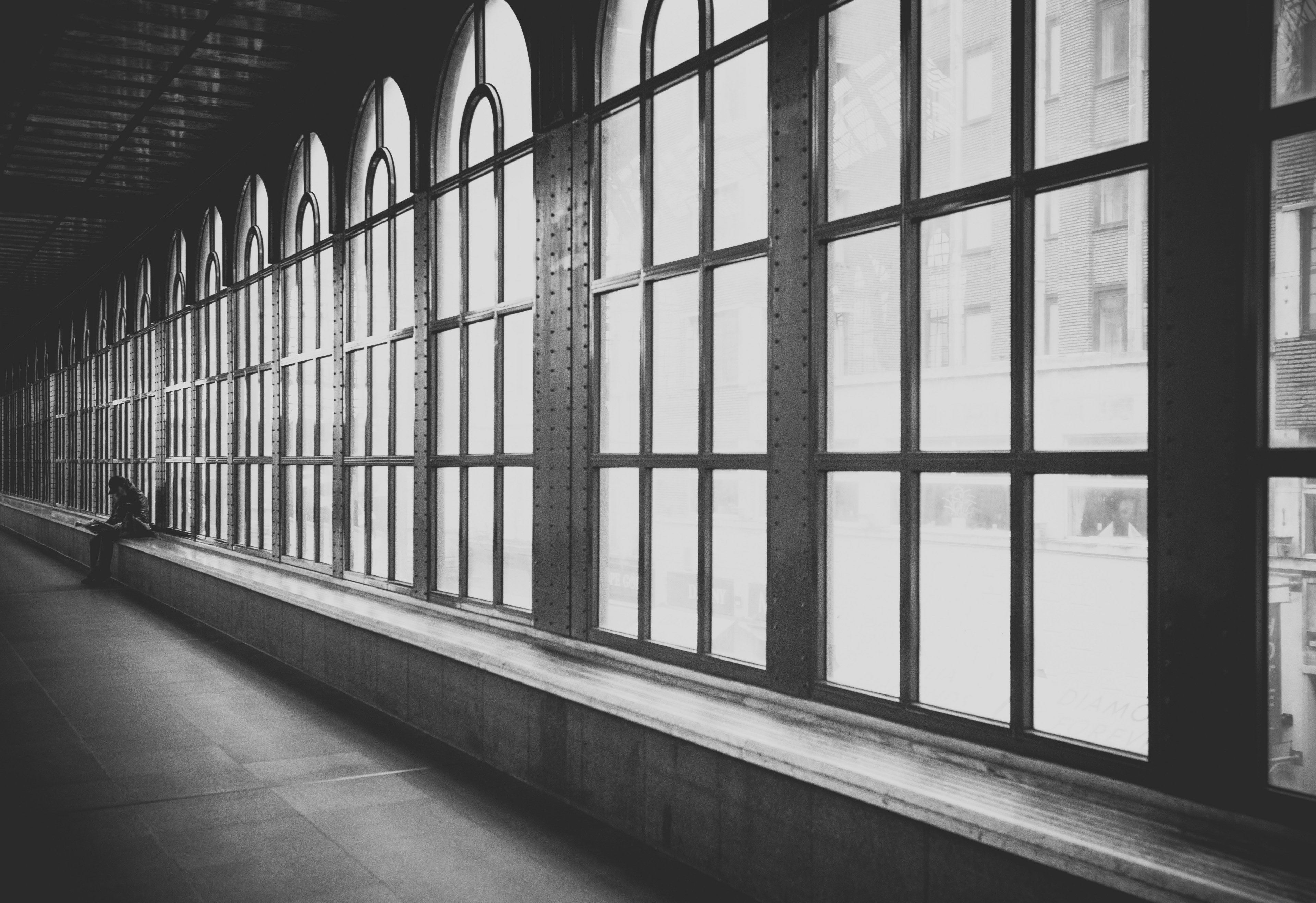 black and white shot of hallway interior with large windows with person sitting, person sitting in hallway 4k, HD Wallpaper