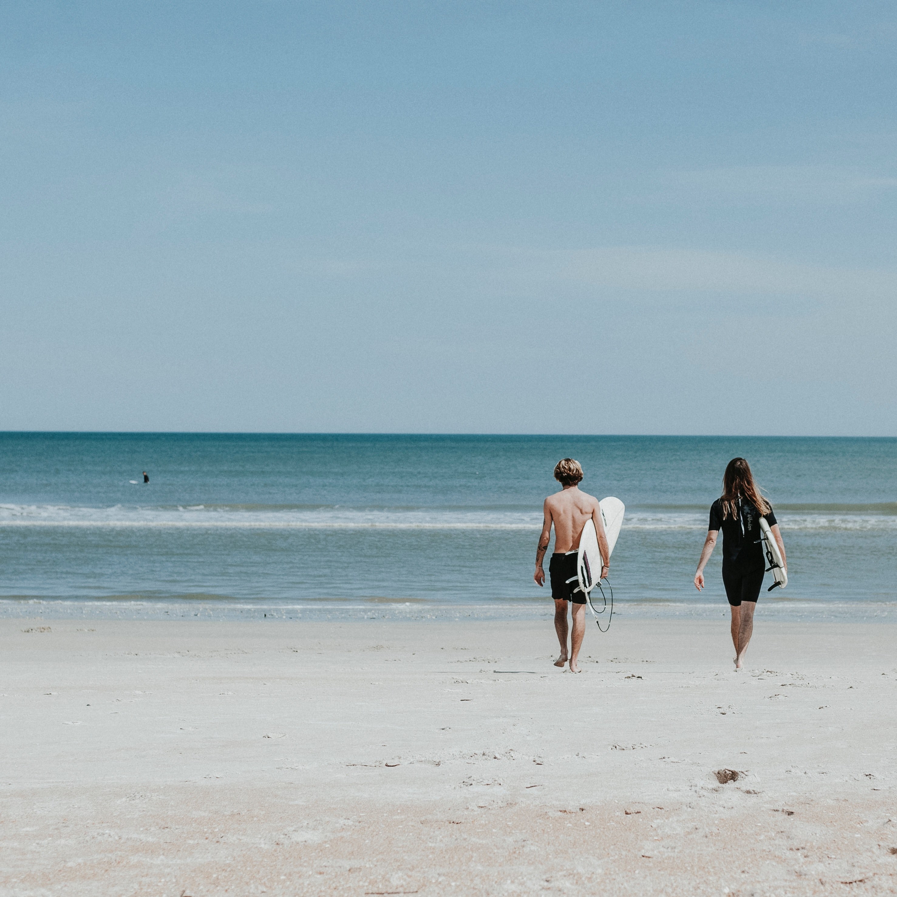 a young man and a woman with surfboards walking towards the sea on a sandy beach, surfer couple on vacation 4k, HD Wallpaper