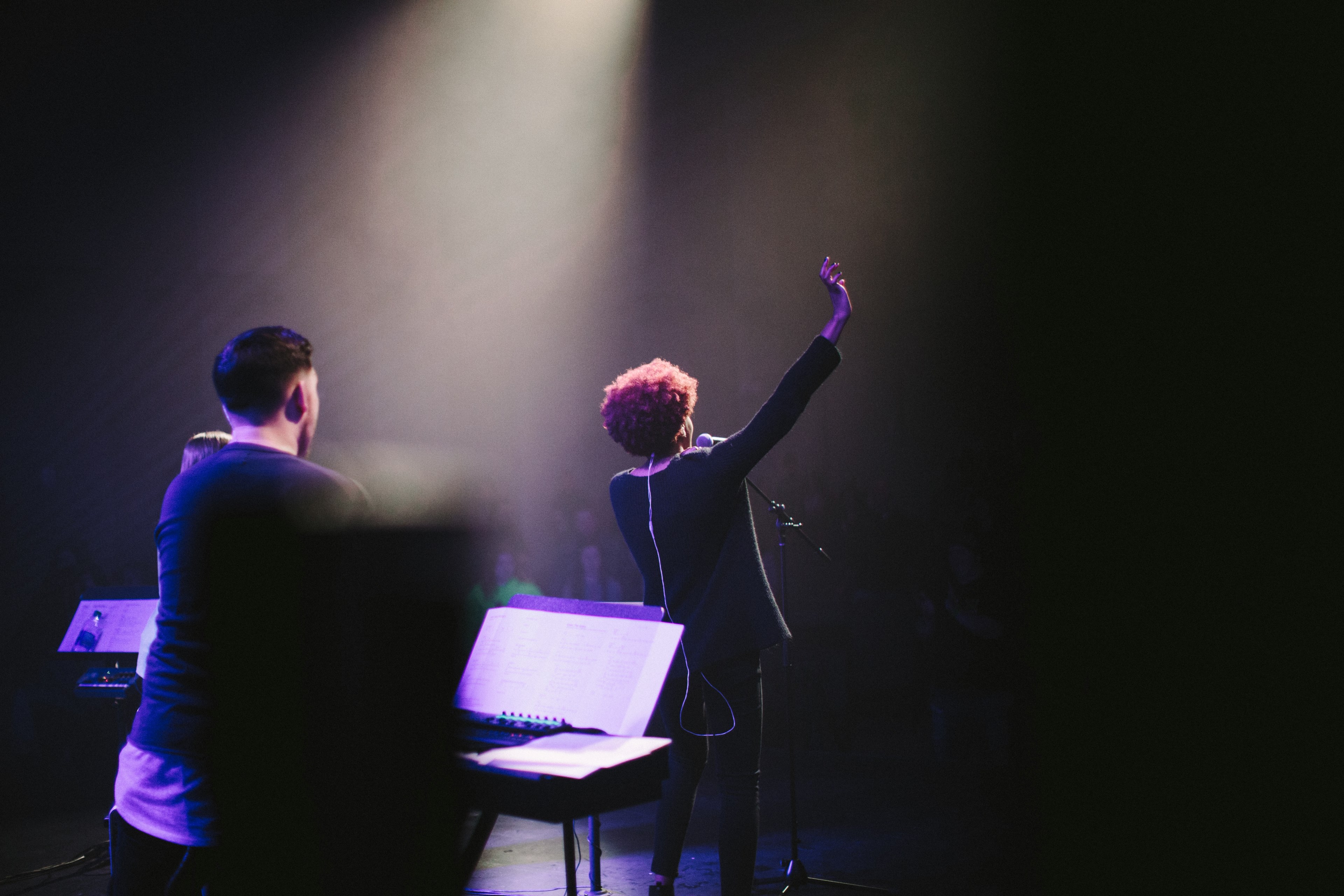 a woman at a microphone raises her hand on a dim stage, female vocalist waving 4k, HD Wallpaper