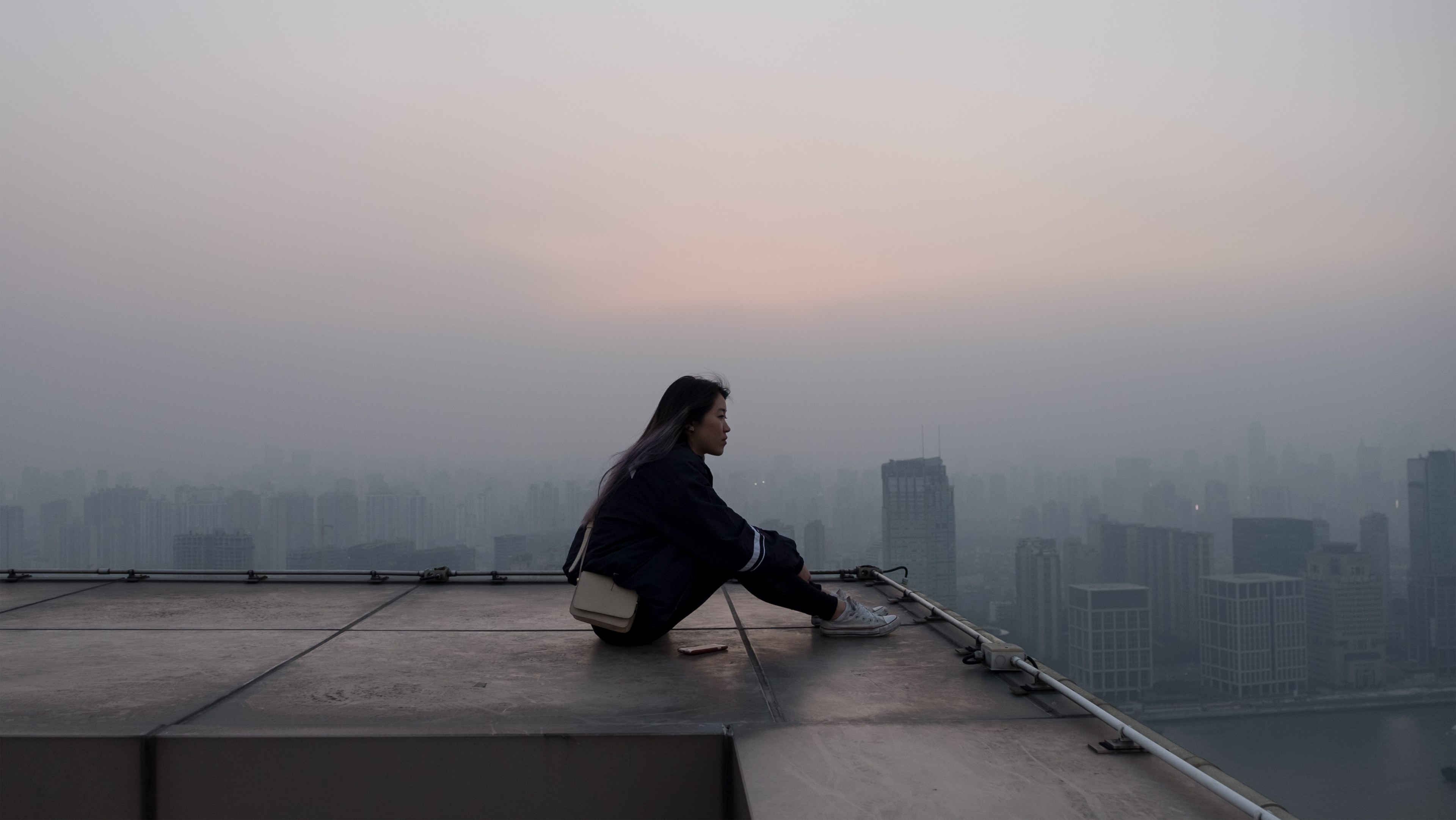 a woman sits looking into the foggy distance atop a building in shanghai, in search of cinematic sunsets 4k, HD Wallpaper