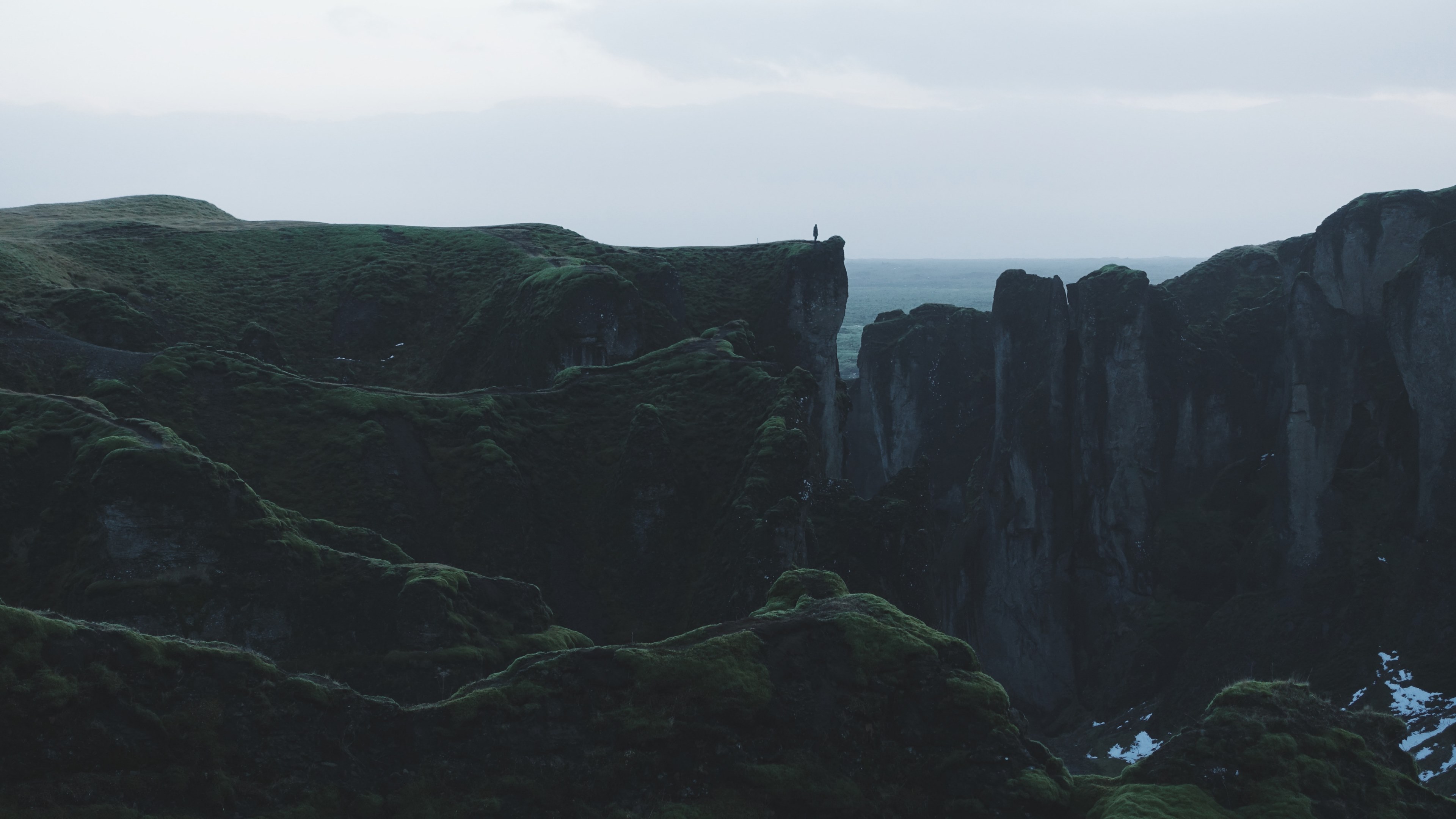 a distant shot of a lone silhouette standing on the edge of a rocky cliff, on the edge of a cliff 4k, HD Wallpaper