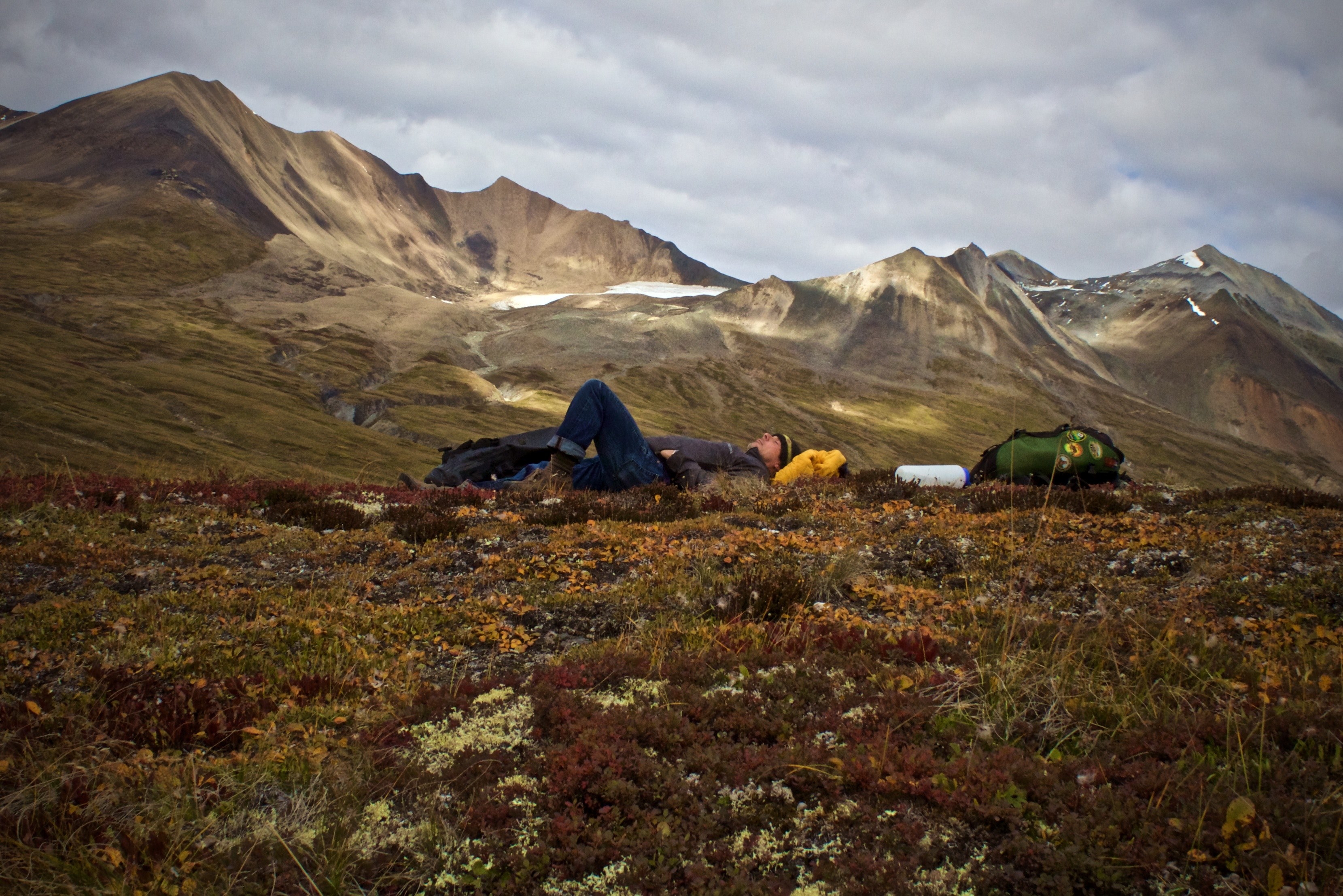 a male backpacker lying down on a meadow in the mountains, resting by samuel glacier 4k, HD Wallpaper