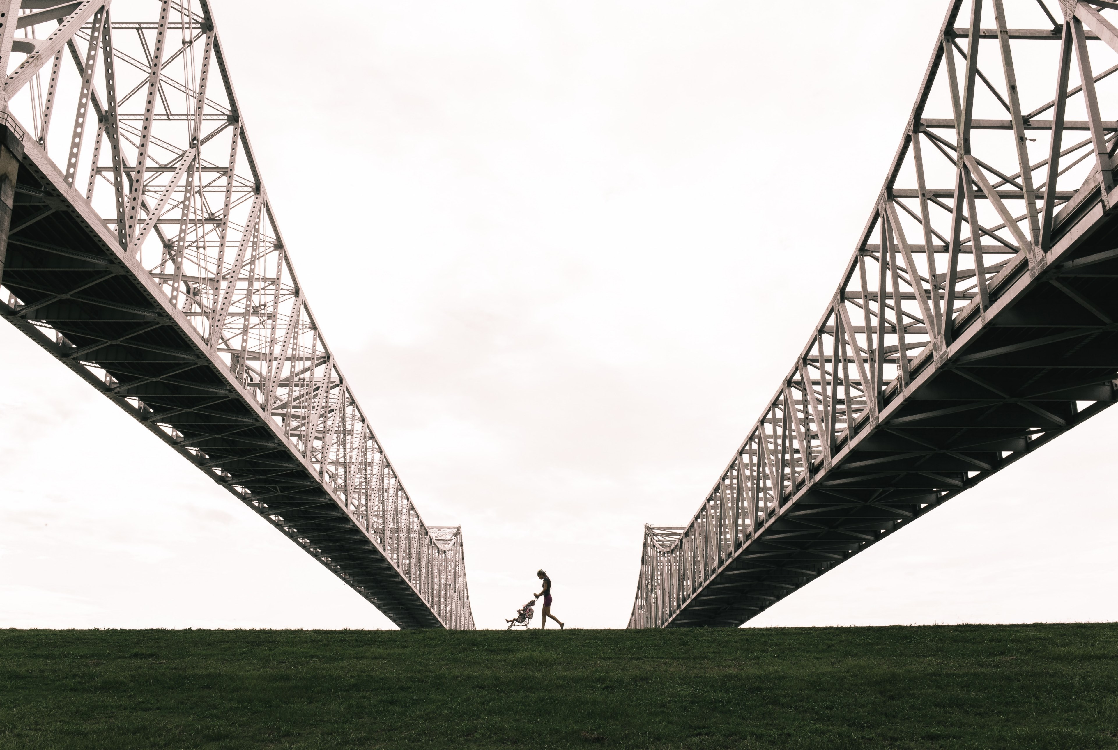 a mother pushing a stroller between the steel arches of a suspension bridge in new orleans, stroller under the suspension bridge 4k, HD Wallpaper