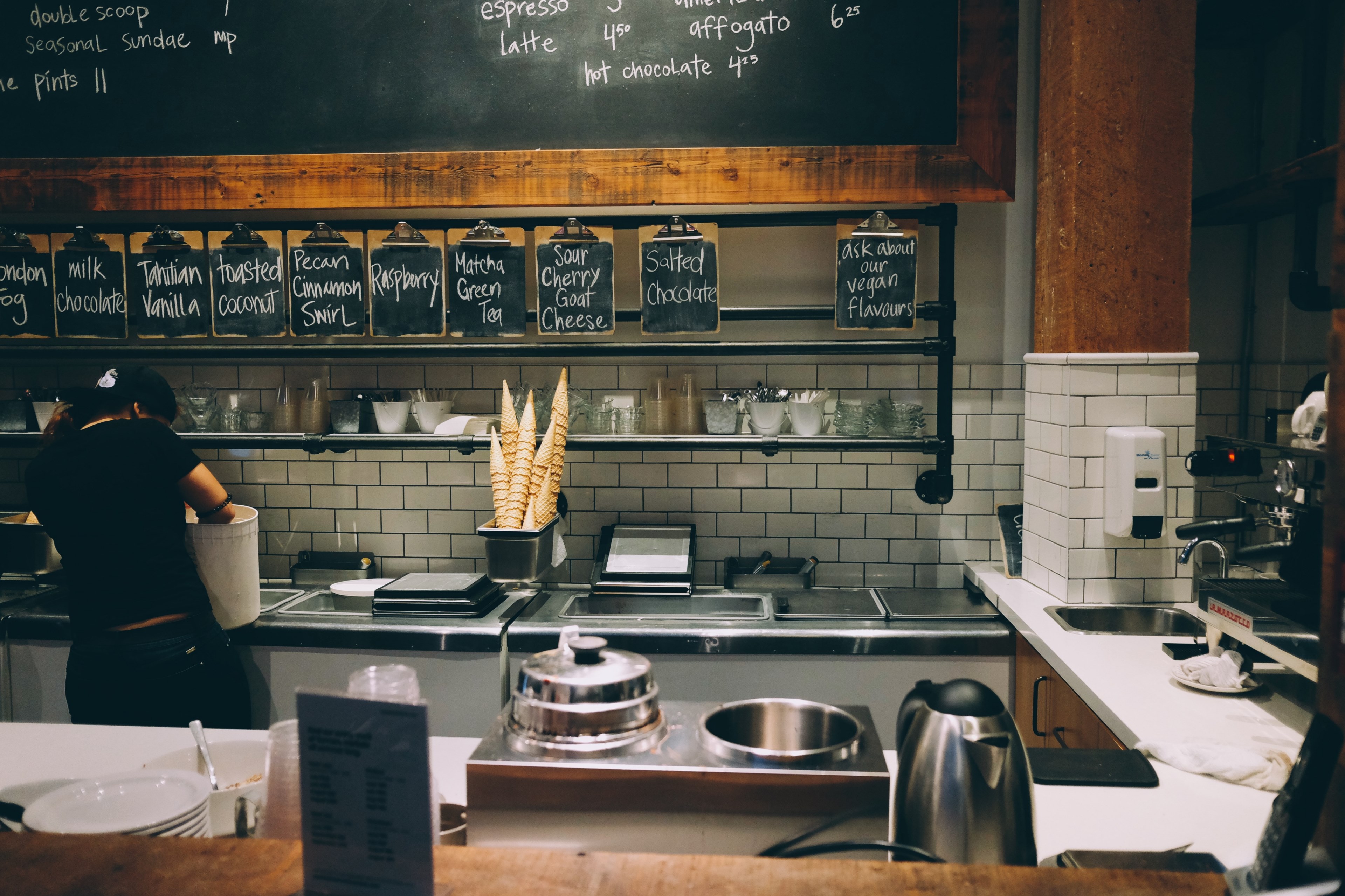 a woman standing back to camera behind the counter in an ice cream parlour, ice cream parlor counter 4k, HD Wallpaper