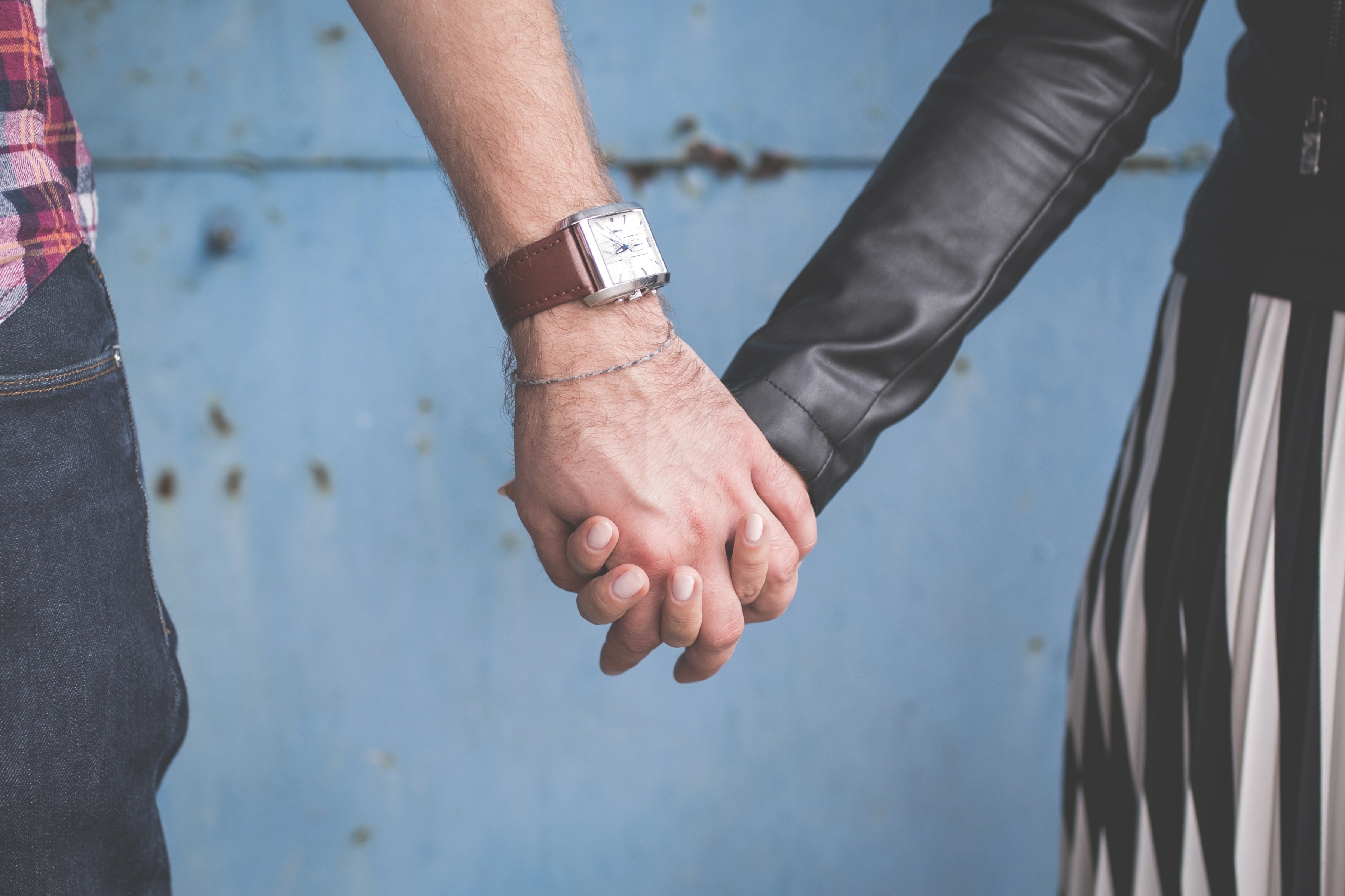 a couple links fingers in front of a blue wall in olsztyn, holding hands by wall 4k, HD Wallpaper