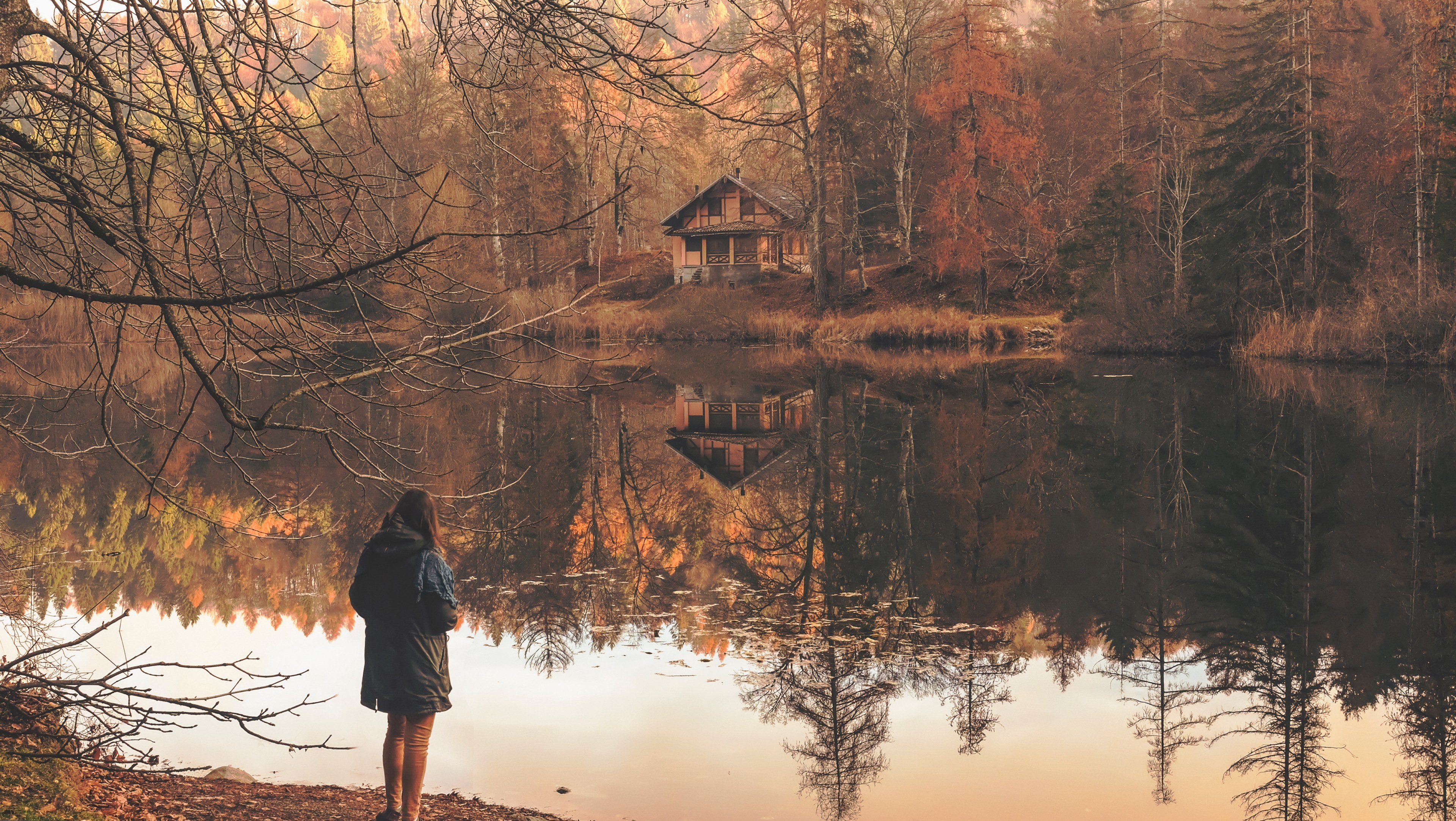 a woman standing on a lakes shore looking off into a cabin on the other shore, woman over an autumn lake 4k, HD Wallpaper