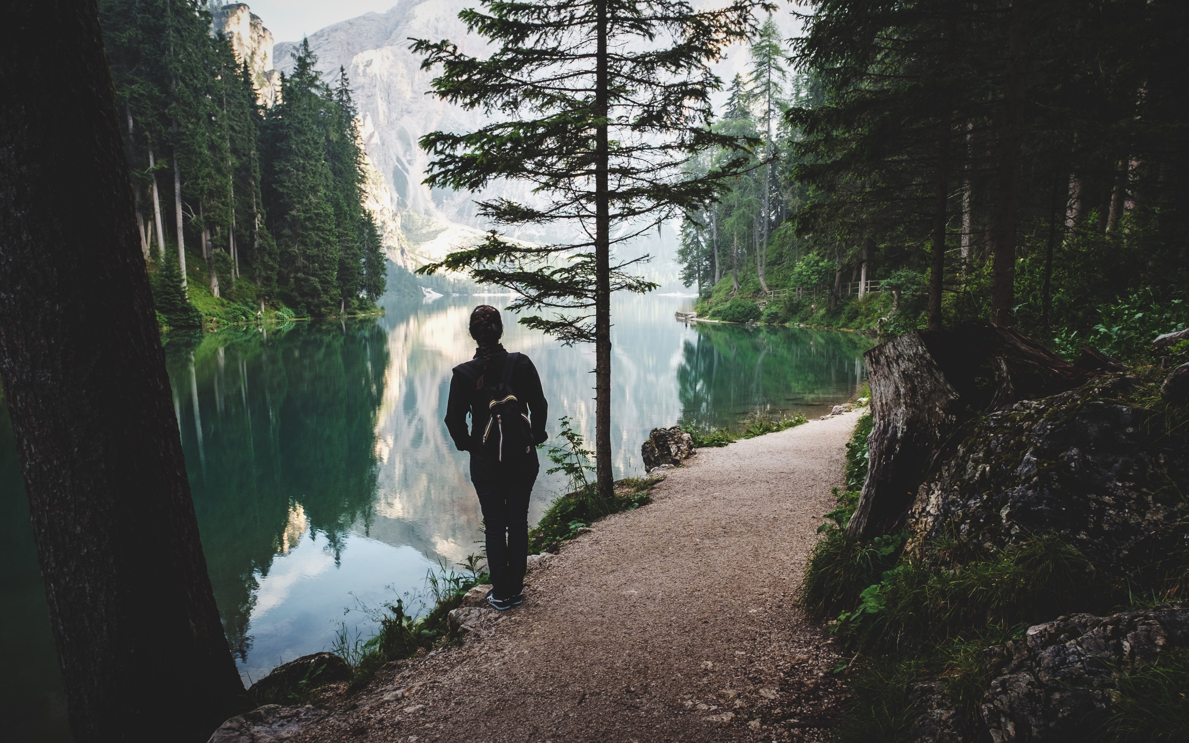 a woman on a path along a still lake in the mountains, on a lakeside path 4k, HD Wallpaper