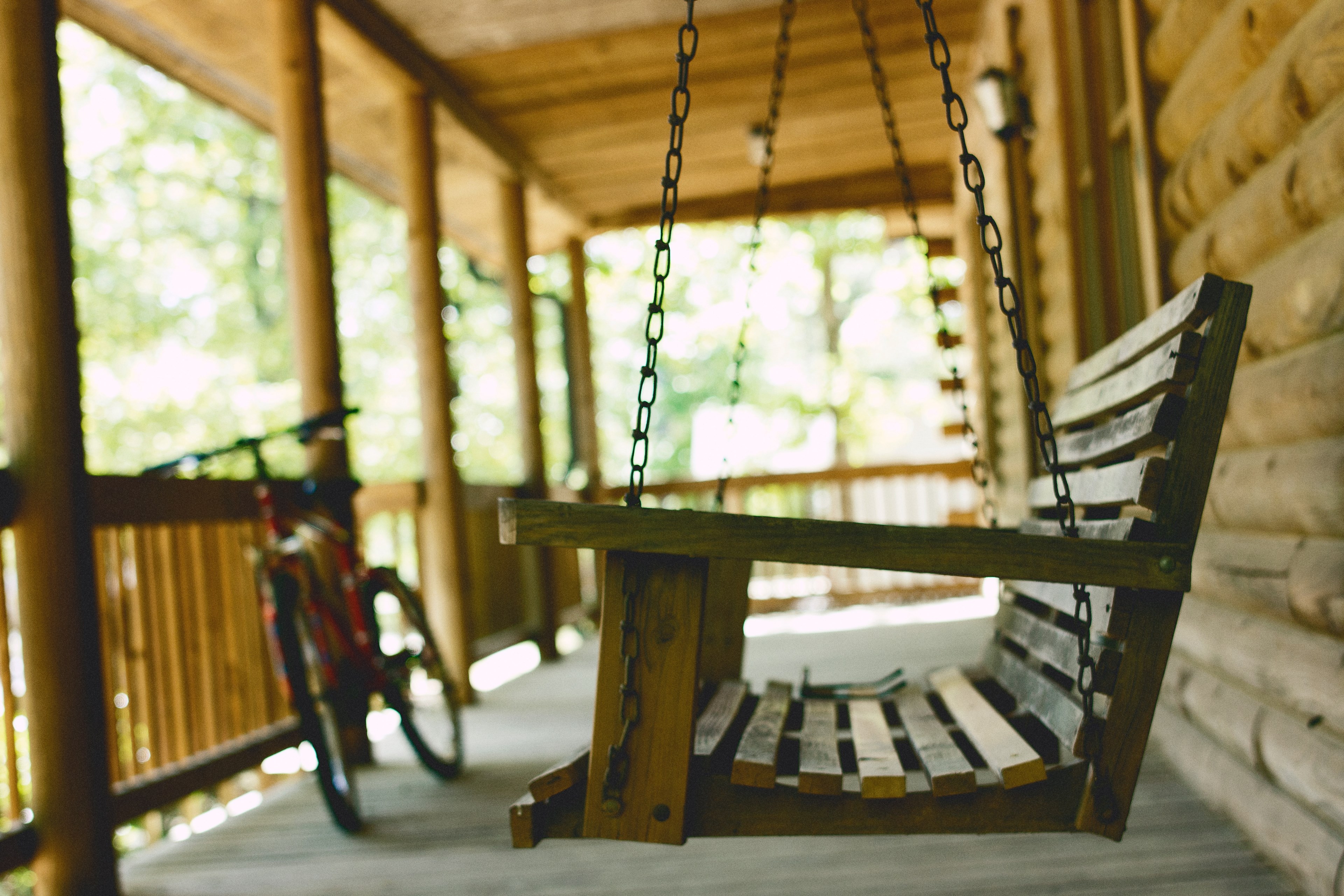 a swing and a bike on the porch of a cabin, swing in cabin porch 4k, HD Wallpaper
