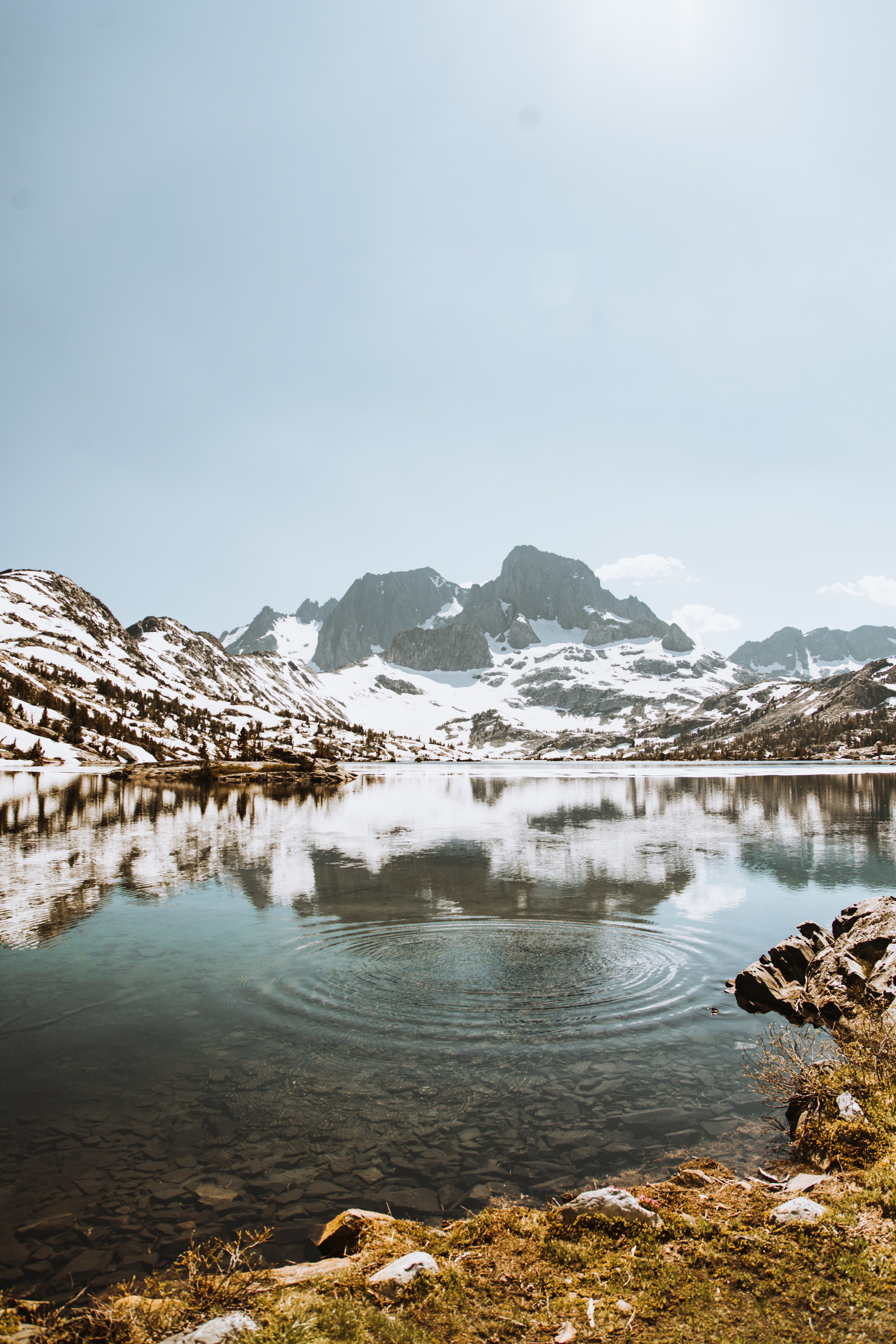 a crystal clear garnet lake with snowy mountains in the distance, snow caps 4k, Phone HD Wallpaper