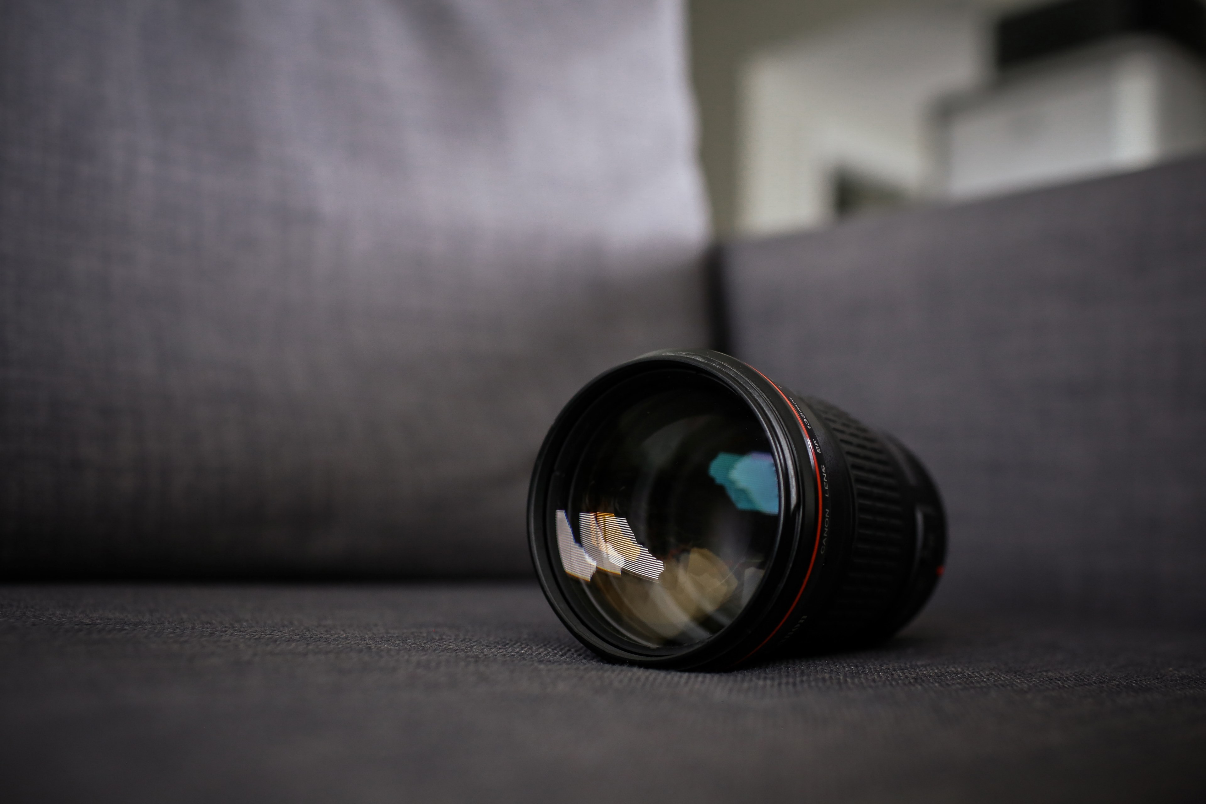 black camera lens sits on gray sofa, camera on sofa 4k, HD Wallpaper