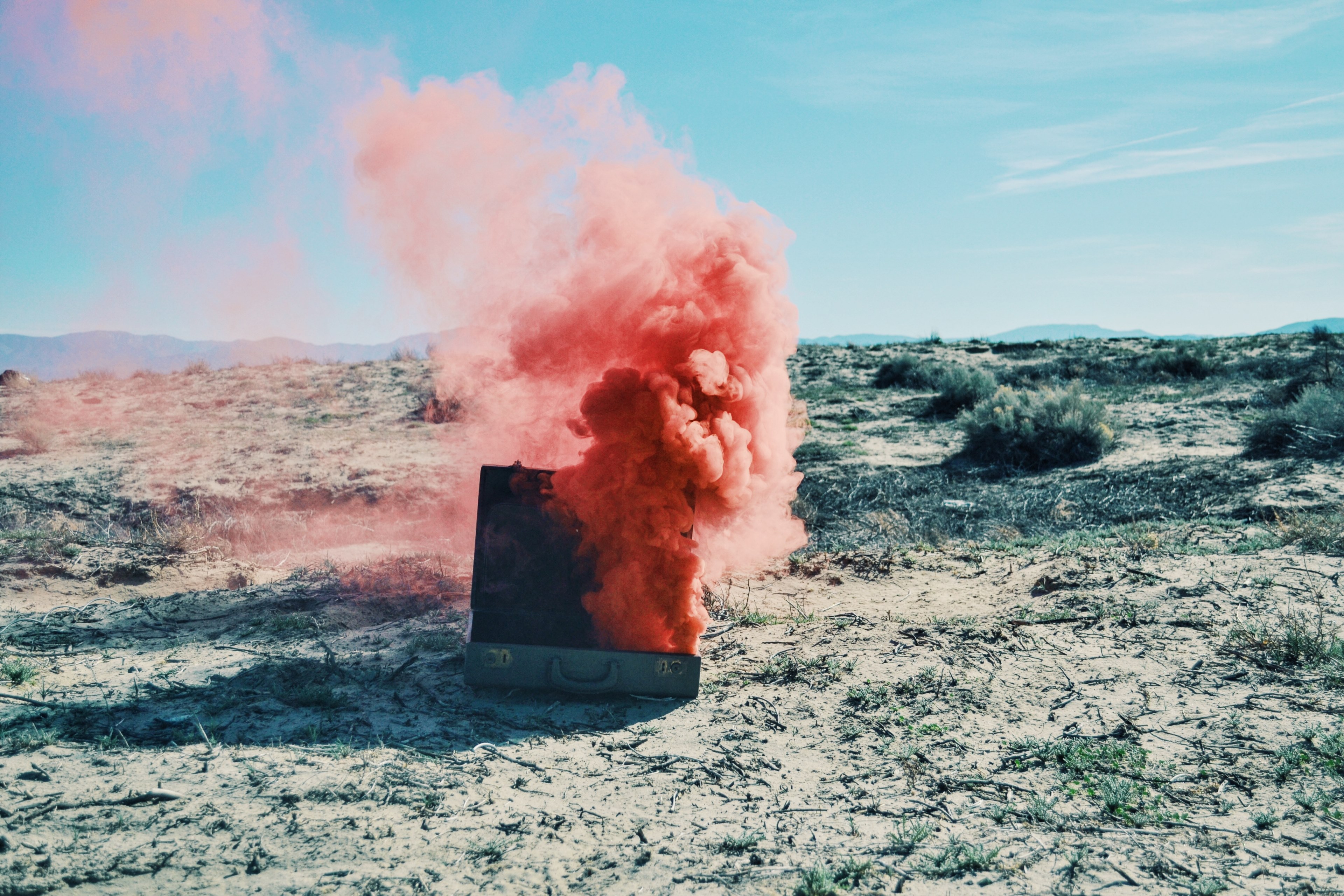 red smoke billows from a suitcase in a sandy desert, pink smoke in the desert 4k, HD Wallpaper