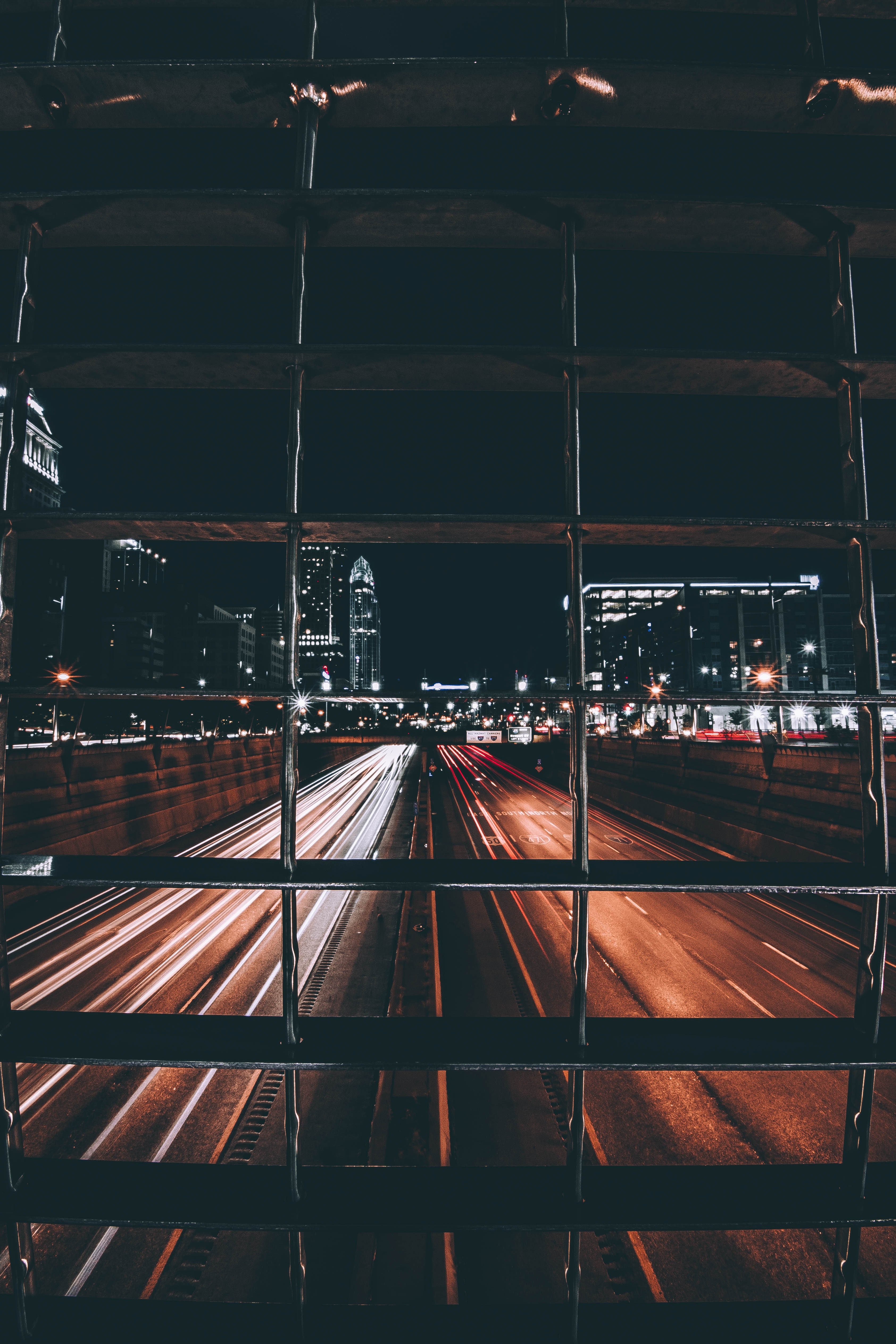 a view of passing headlights on a cincinnati at street from behind a building grill, traffic at night in cincinnati 4k, Phone HD Wallpaper