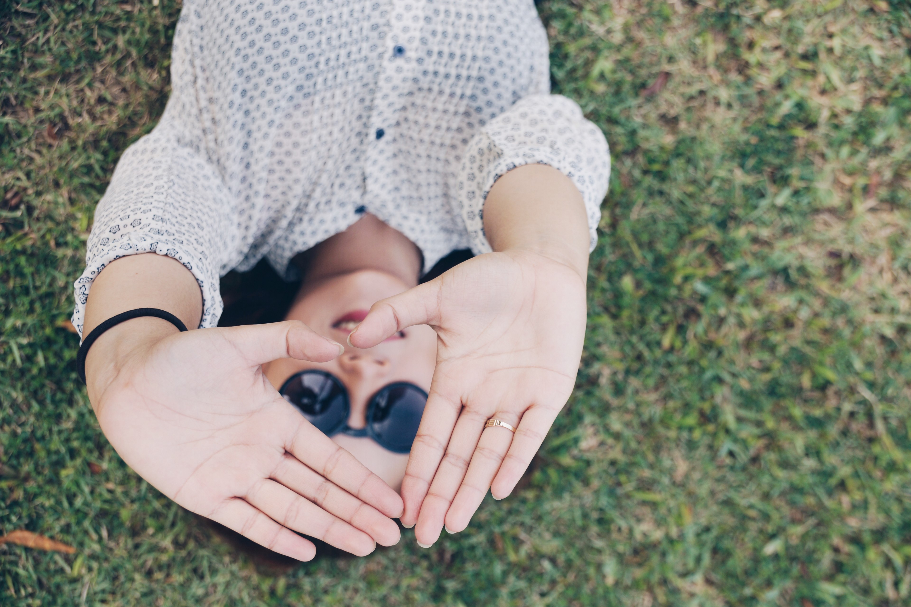a woman laying on grass holds her hands up to make heart shape, hearts perspective 4k, HD Wallpaper