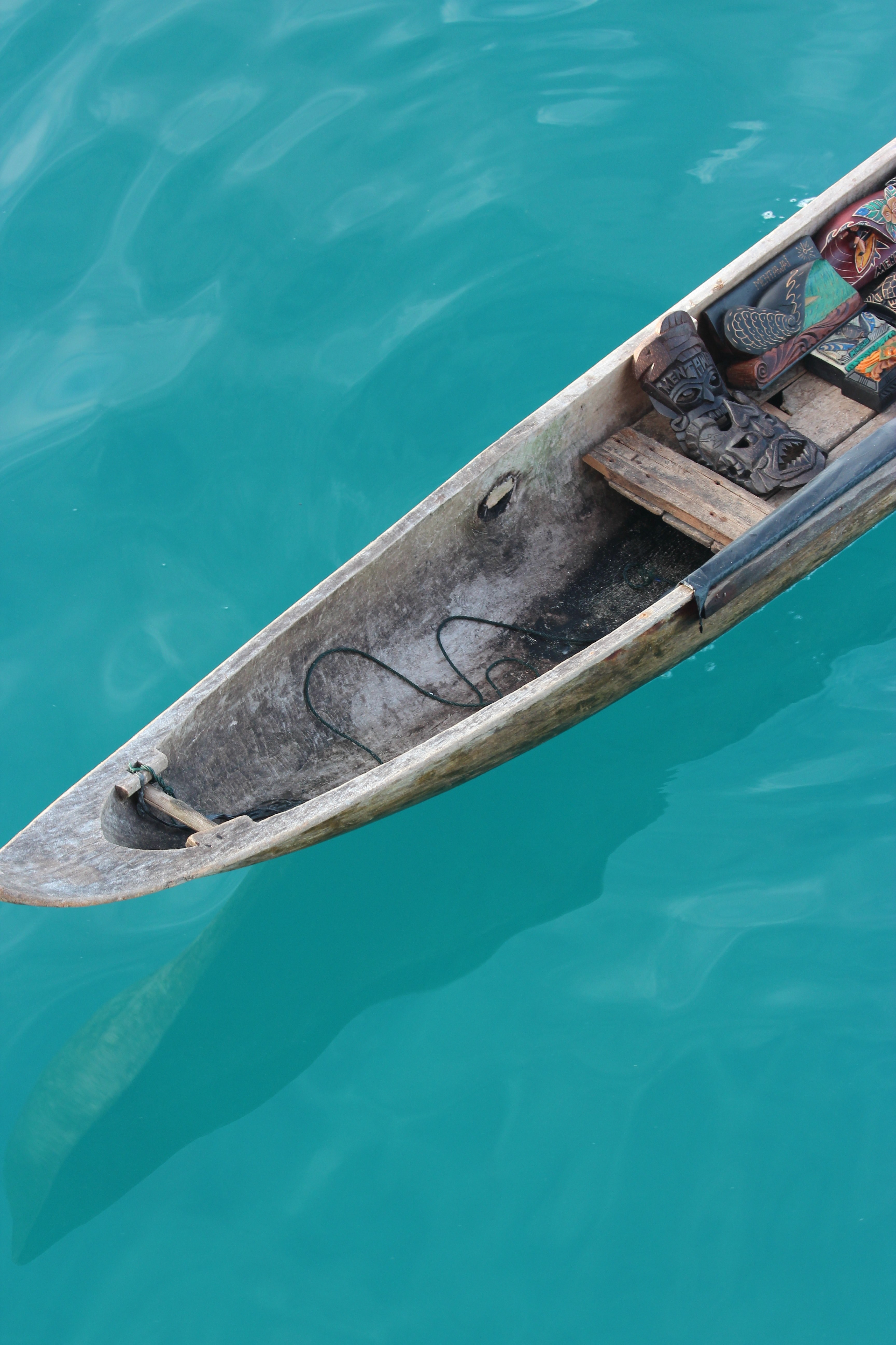 a wooden canoe with tribal masks inside on the azure surface of water, tribal canoe 4k, Phone HD Wallpaper