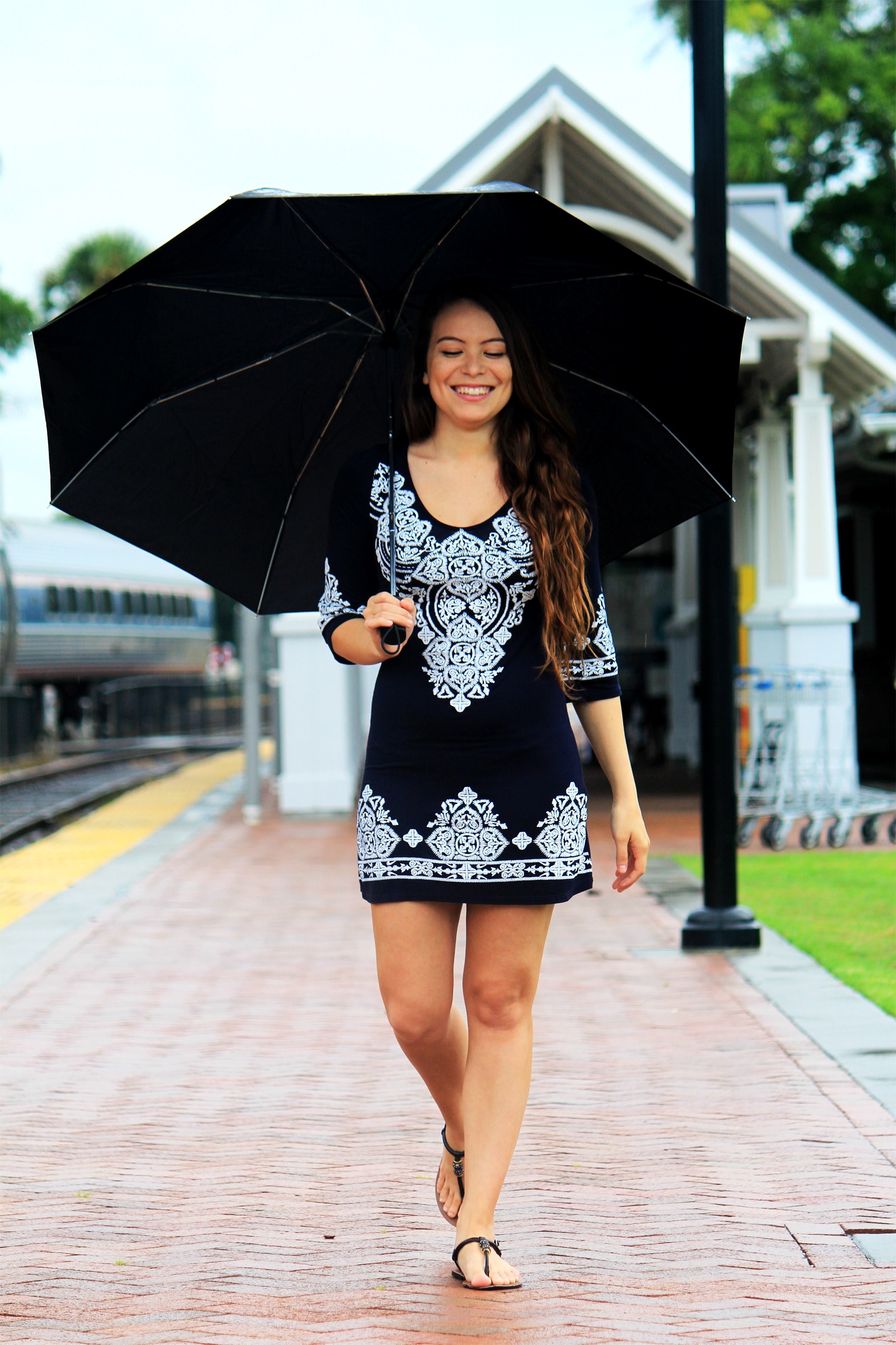 smiling woman in black dress with closed eyes walks along a brick path holding an umbrella, woman with umbrella 4k, Phone HD Wallpaper