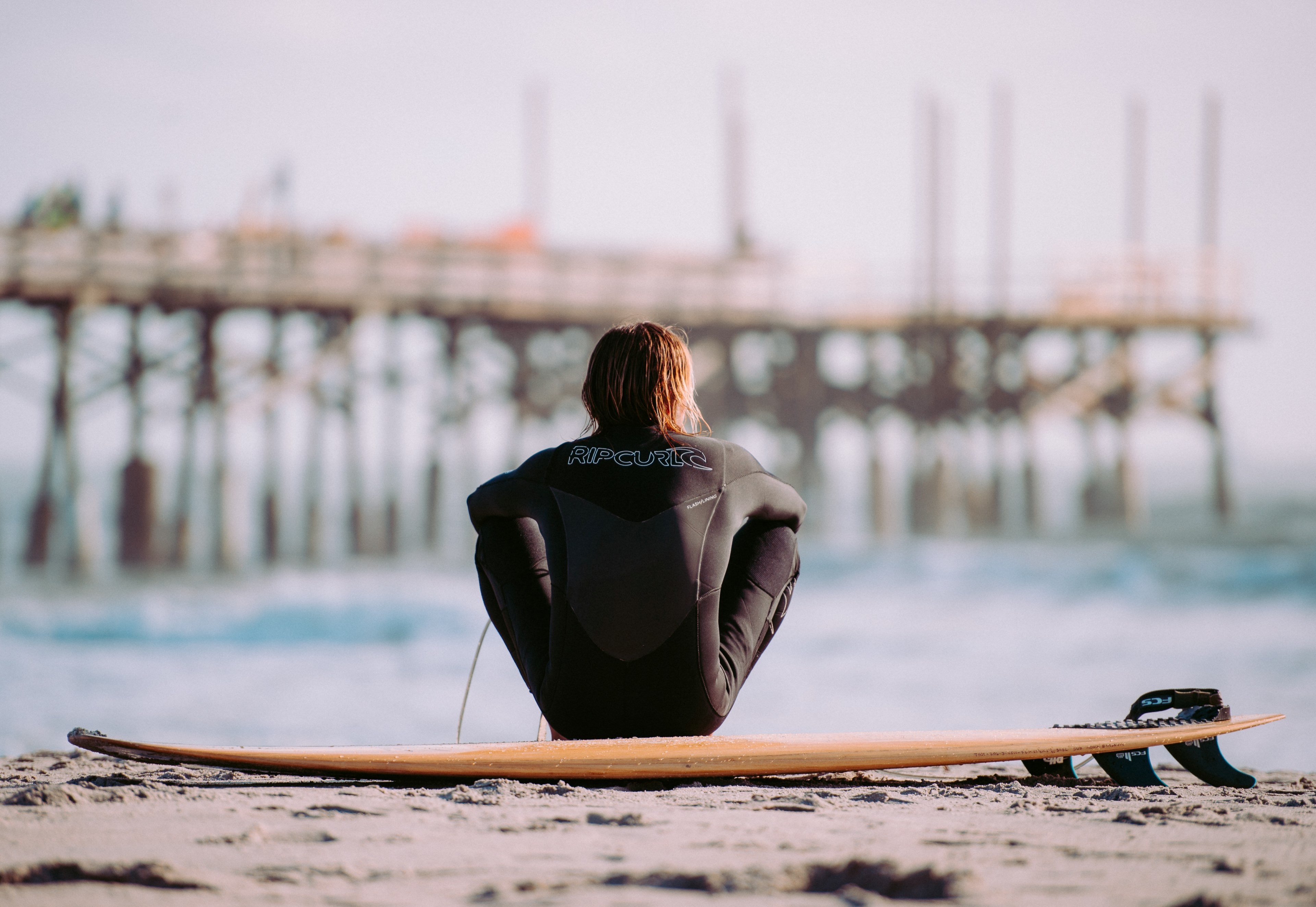 surfer in a wetsuit sitting on the beach by the surfboard at cocoa beach, watching the surf 4k, HD Wallpaper