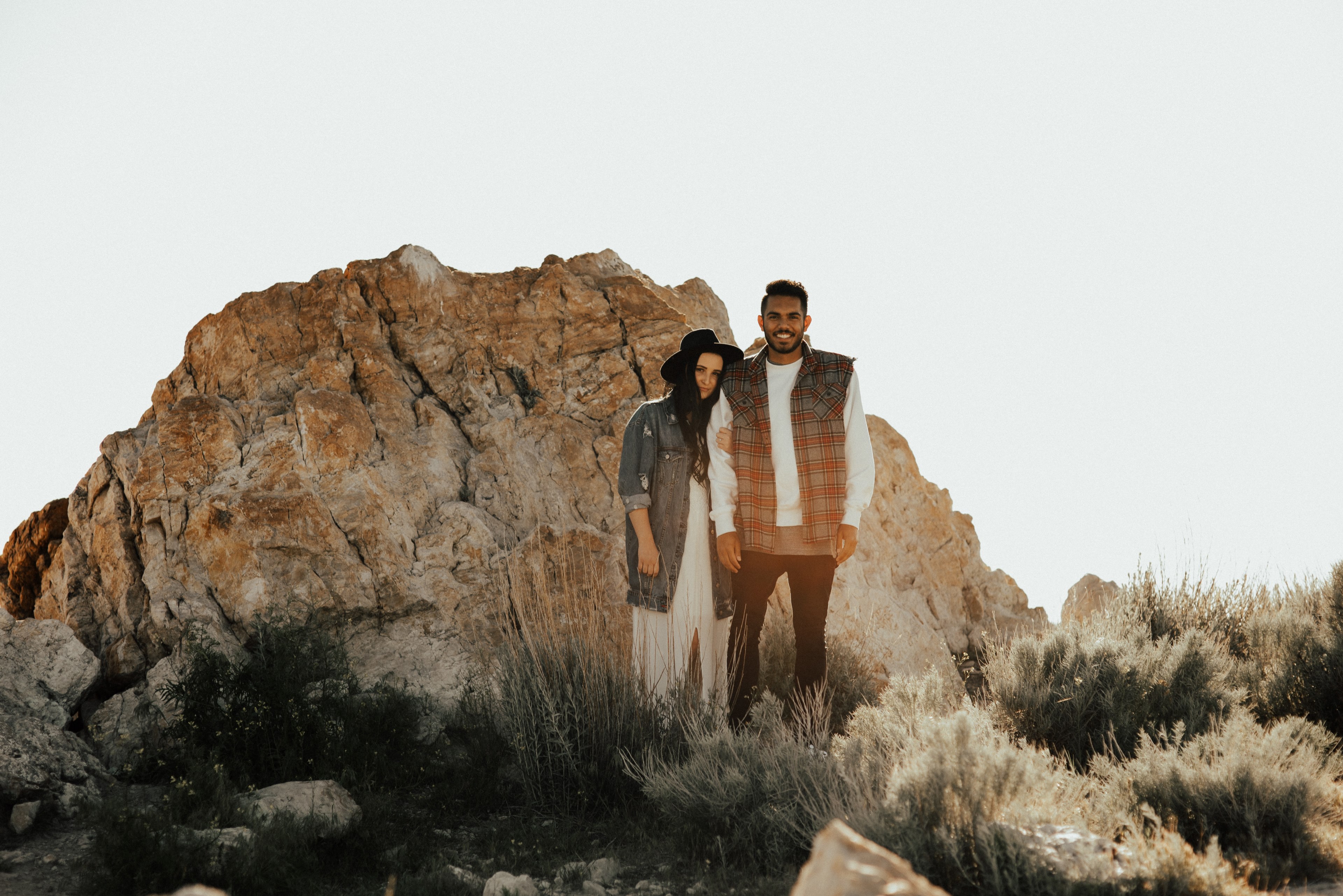 a man and woman stand close in front of large rock at dusk, engaged in the desert 4k, HD Wallpaper