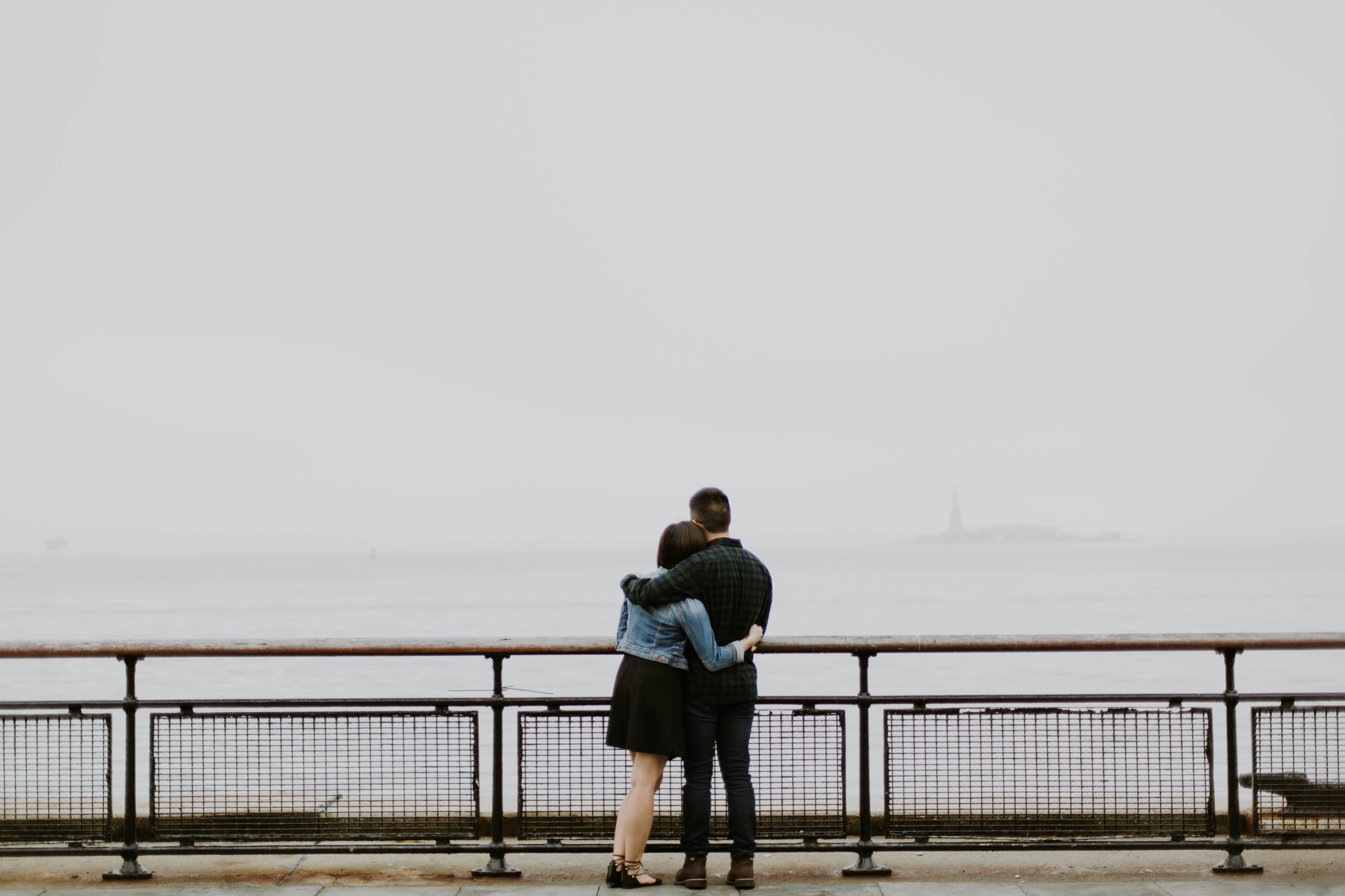 a couple holds one another on a pier overlooking a body of water and overcast sky, hold me 4k, HD Wallpaper
