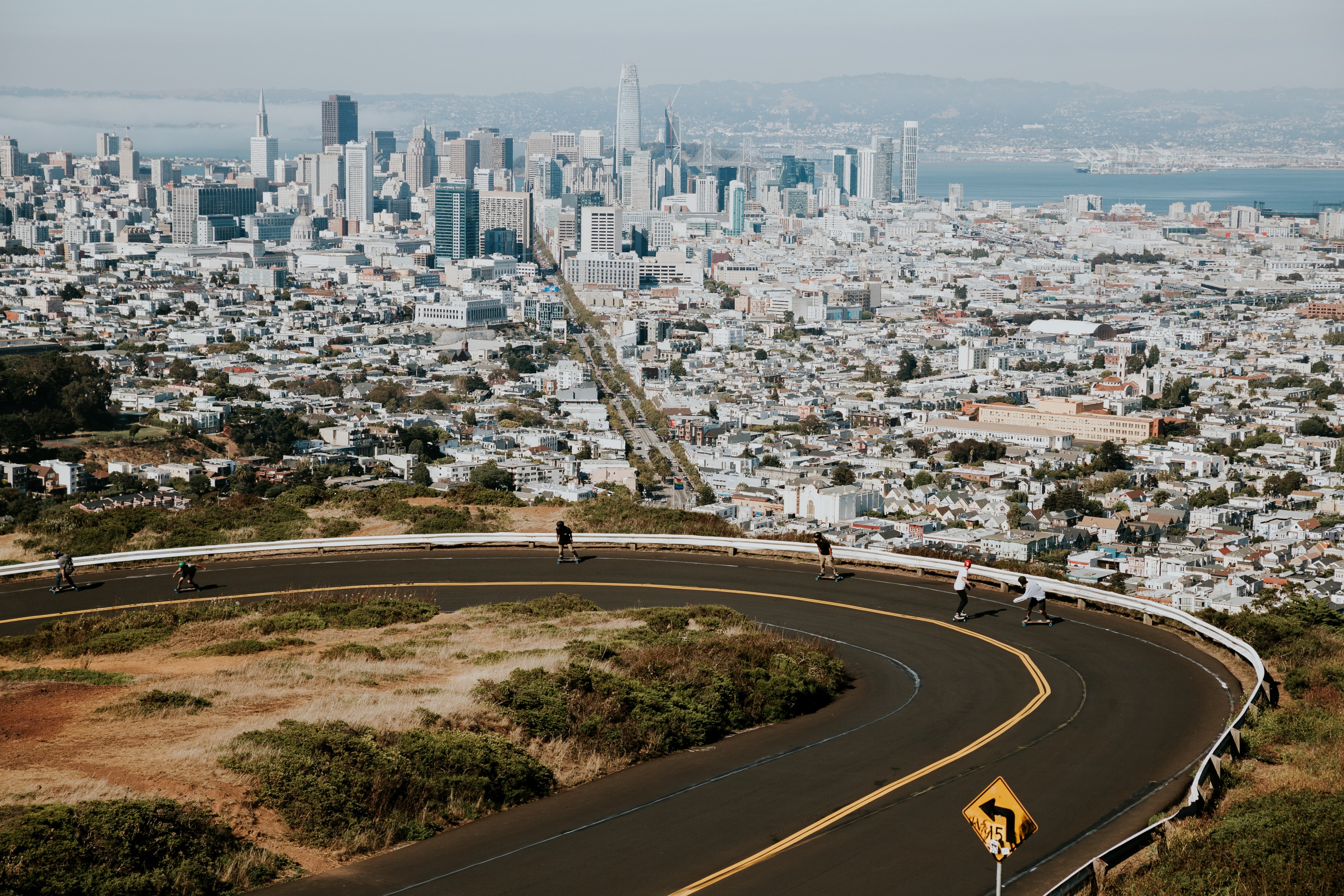 curvy road and kids on skateboard with sprawling cityscape and water behind them, skatin down sf 4k, HD Wallpaper