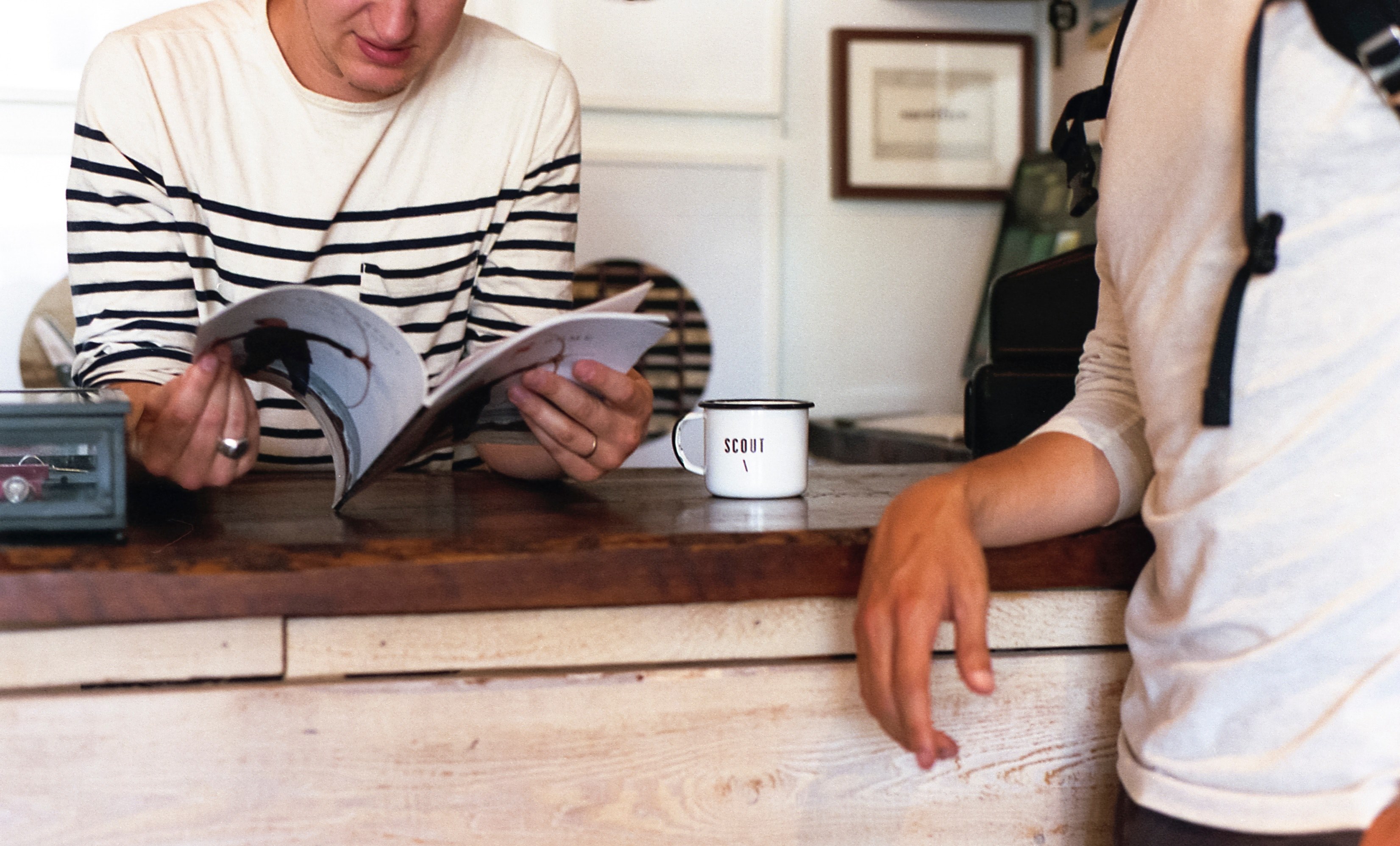 two people standing near a counter with one of them reading a book, two people by a counter 4k, HD Wallpaper