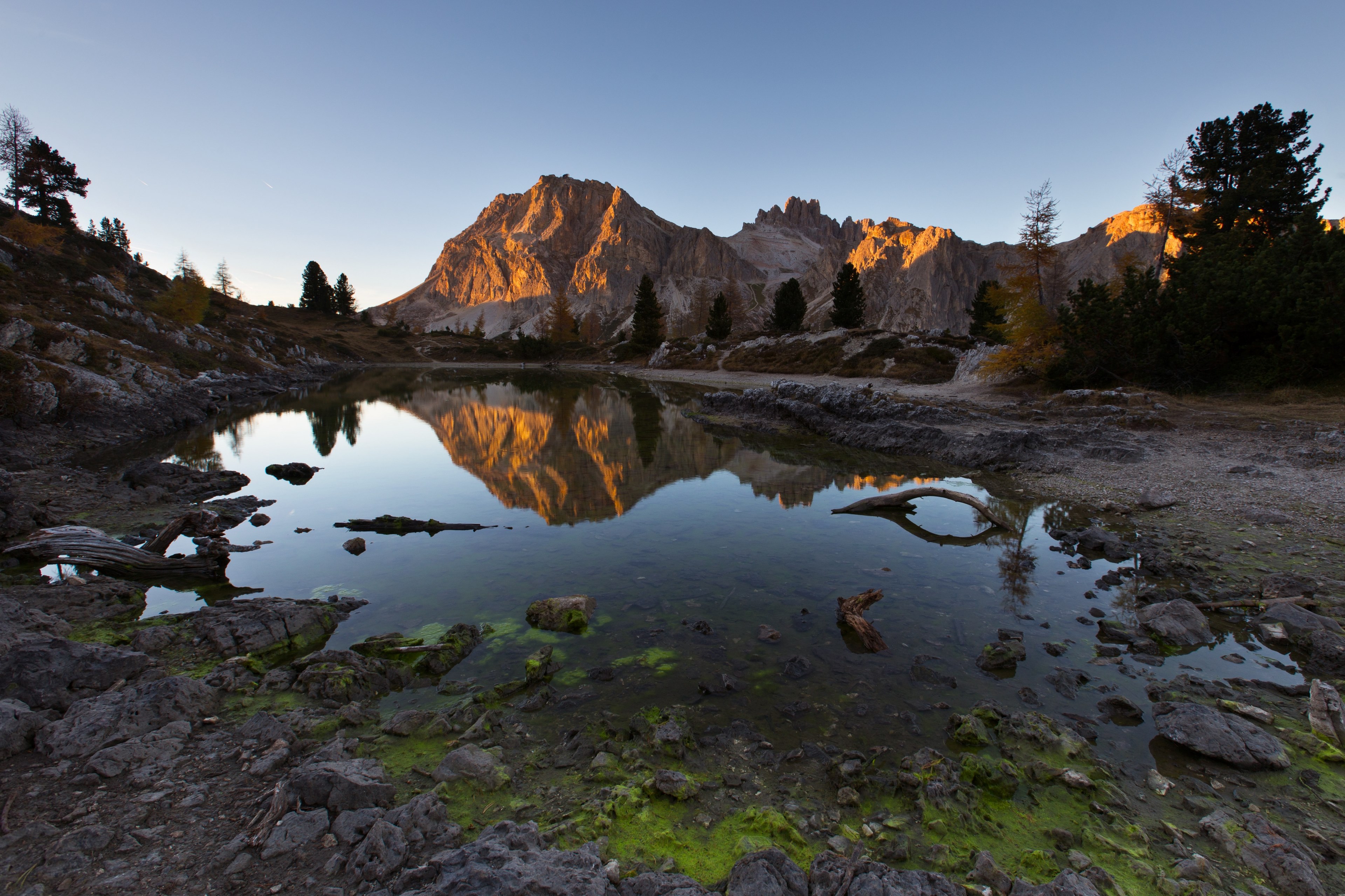 a sunlit rock formation overlooking a small rocky pond, shallow pond at dusk 4k, HD Wallpaper