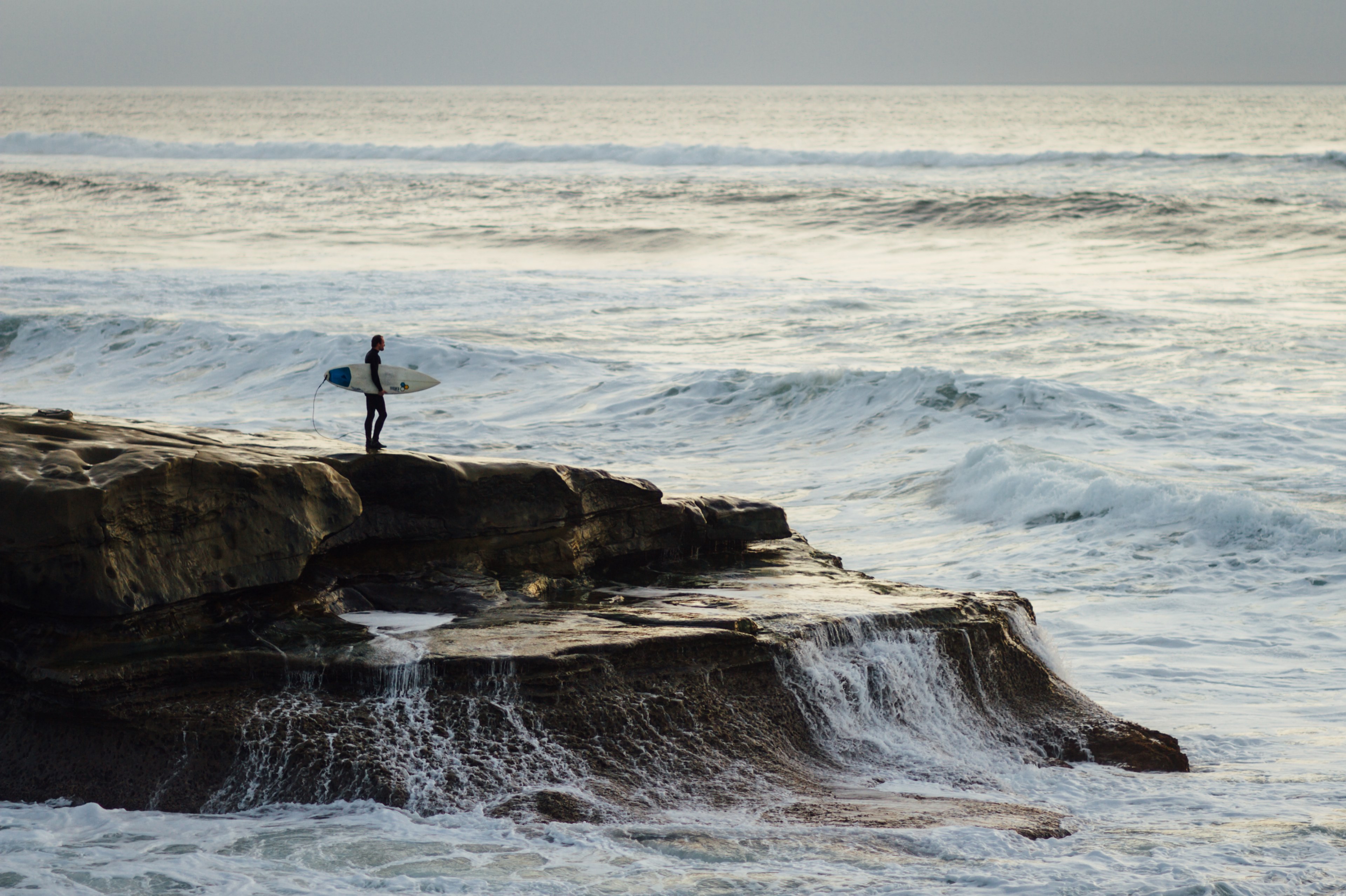 surfer with a surfboard standing on a coastal rock watching rough ocean at ocean beach, sunset surfing 4k, HD Wallpaper