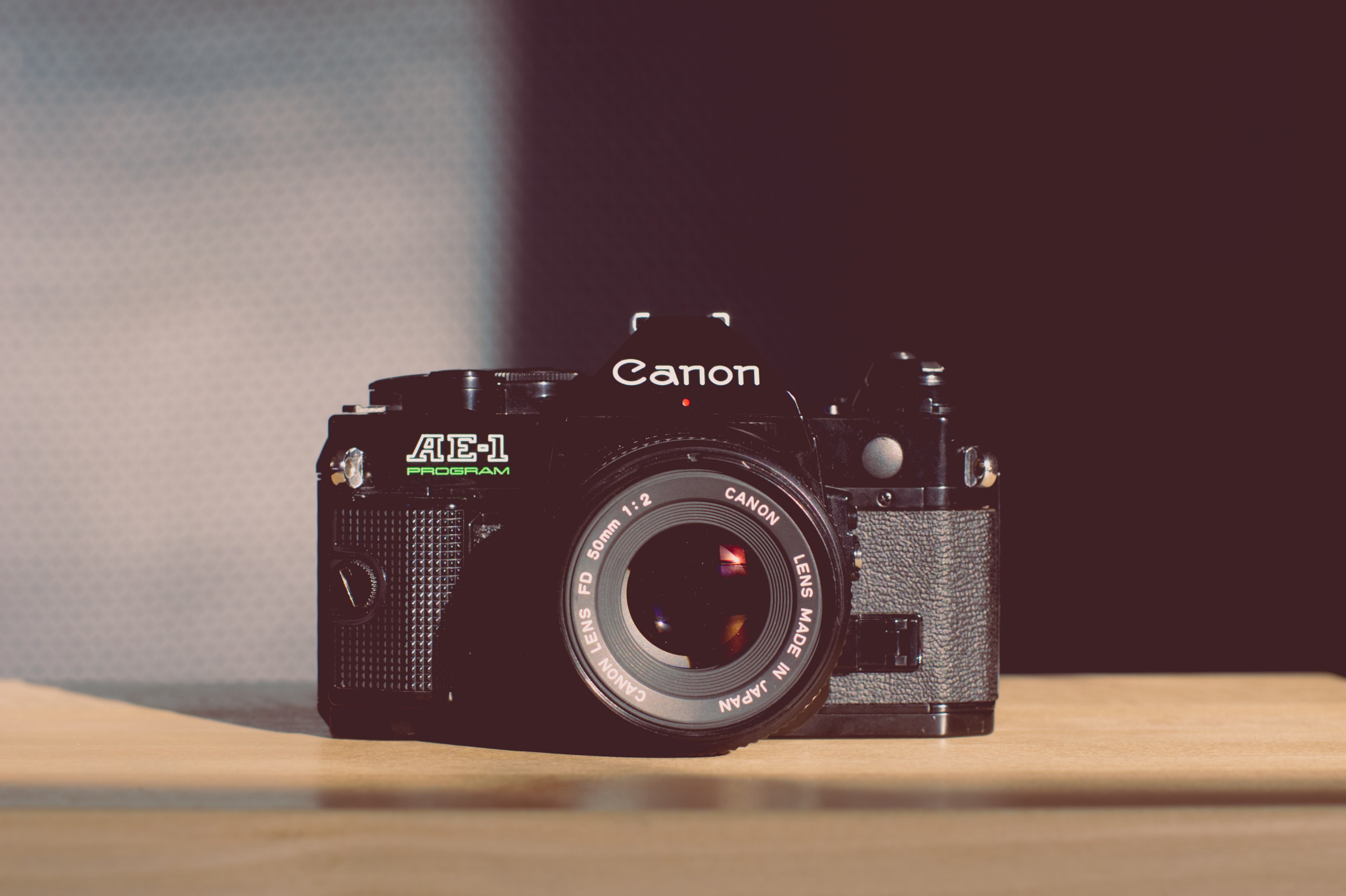 vintage canon ae 1 program with a 50mm lens on a light colored wooden surface beside a partly shadowed wall, canon ae 1 program 4k, HD Wallpaper