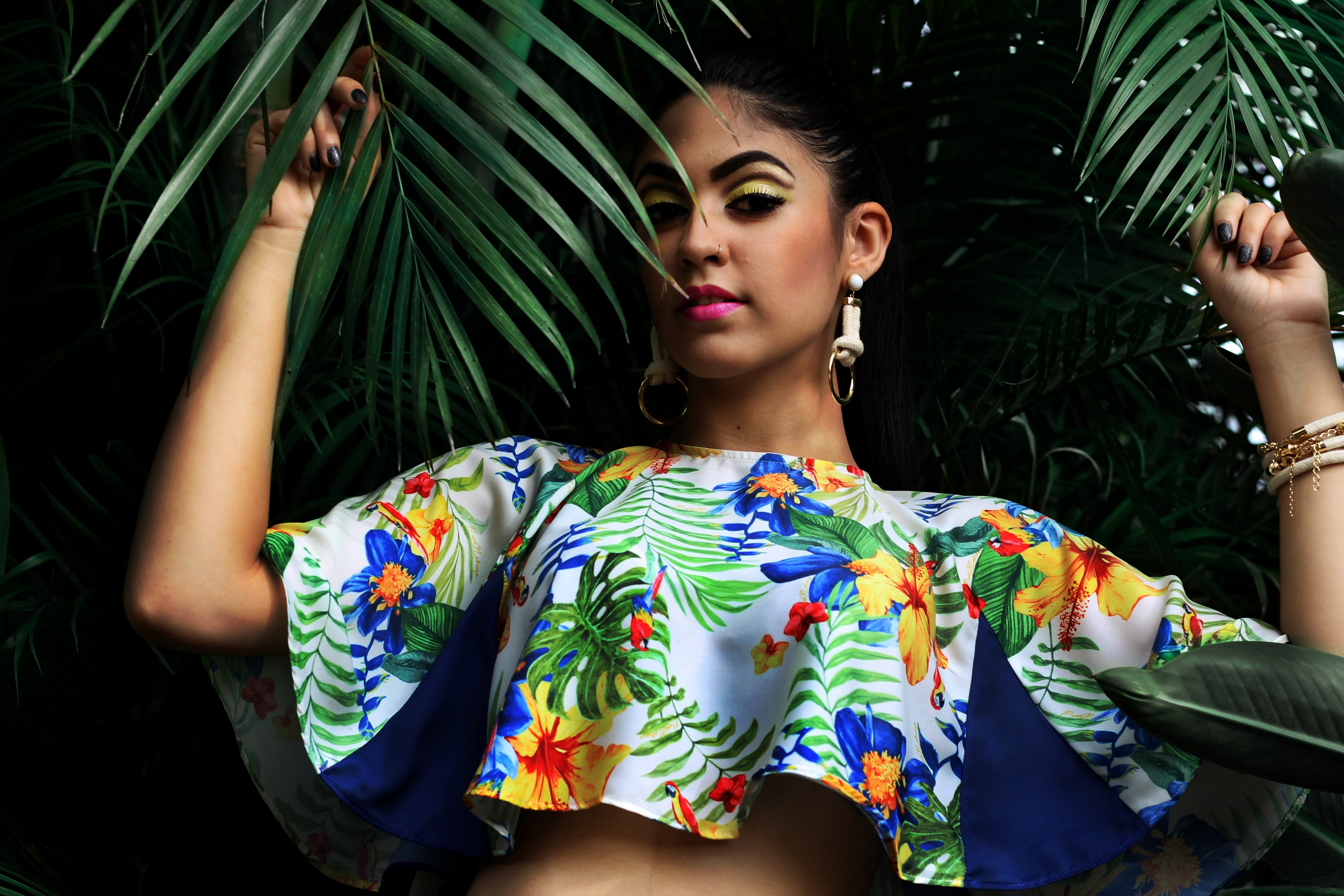 a woman in a vibrant crop top and earrings stands among palm fronds touching the leaves, woman among palm fronds 4k, HD Wallpaper