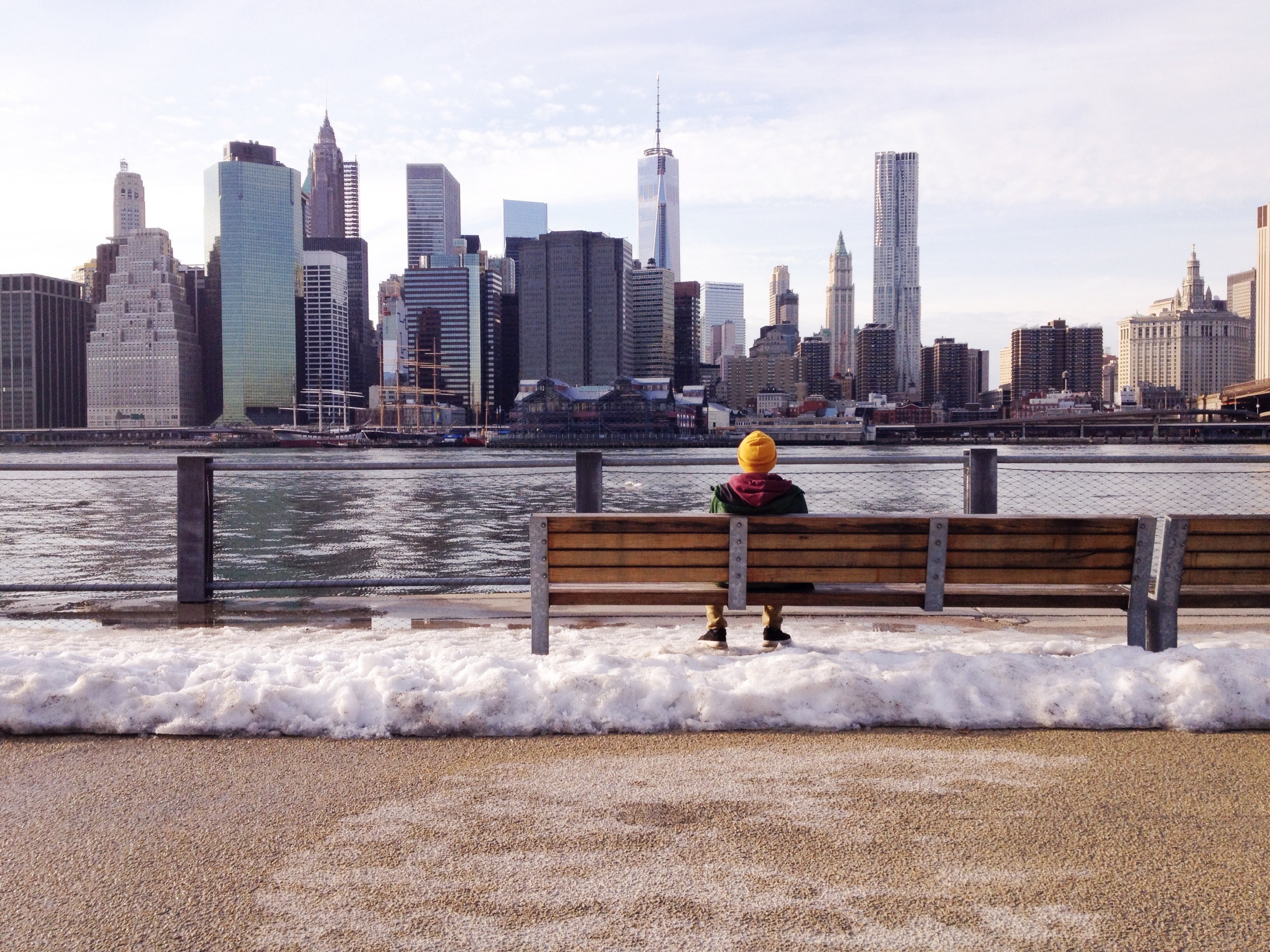 person sits on a bench looking at the water and skyscrapers of new york city, lunch break 4k, HD Wallpaper