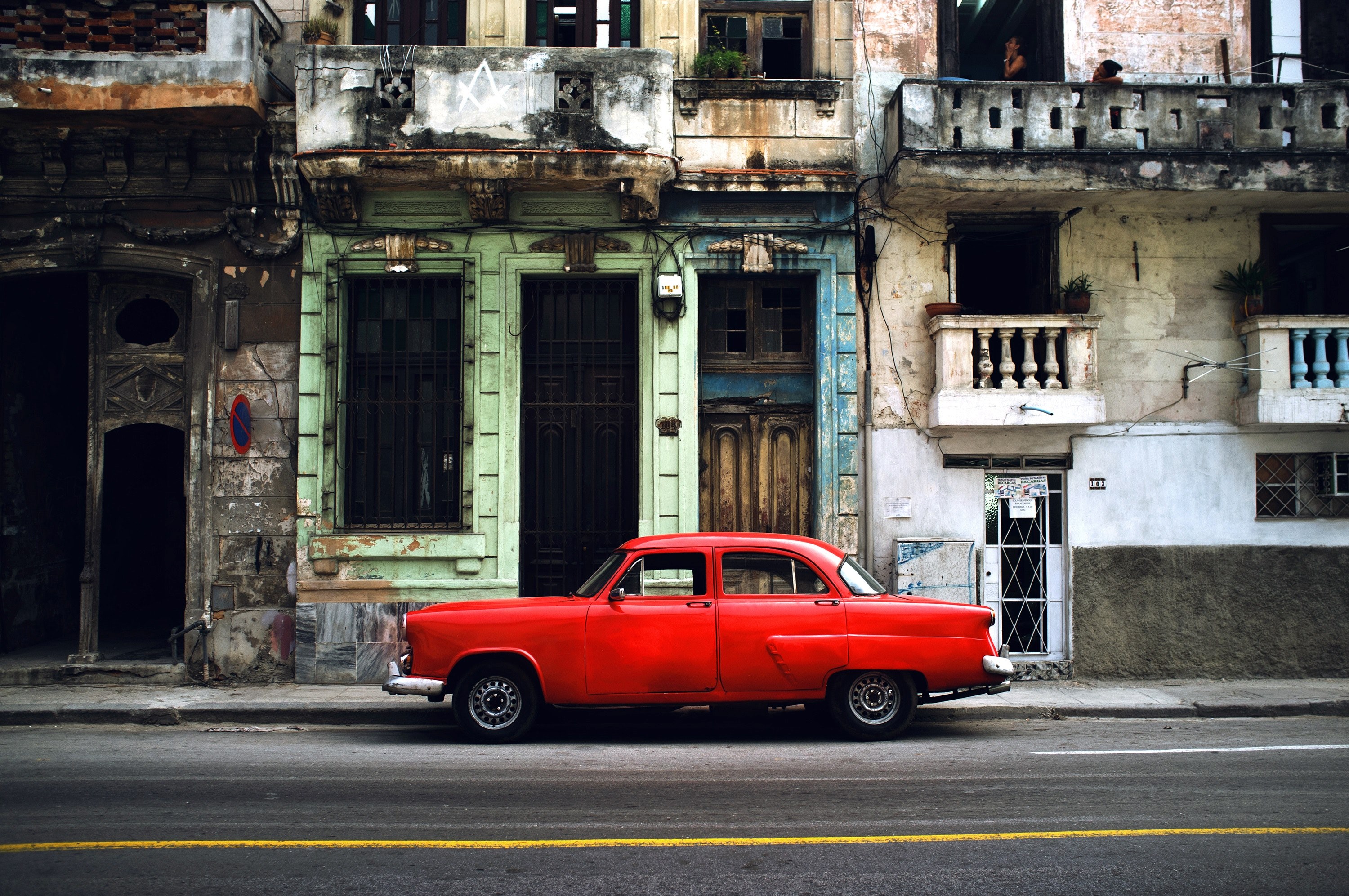 a red car driving in an old urban city habana vieja, vintage car parked in front of old buildings 4k, HD Wallpaper