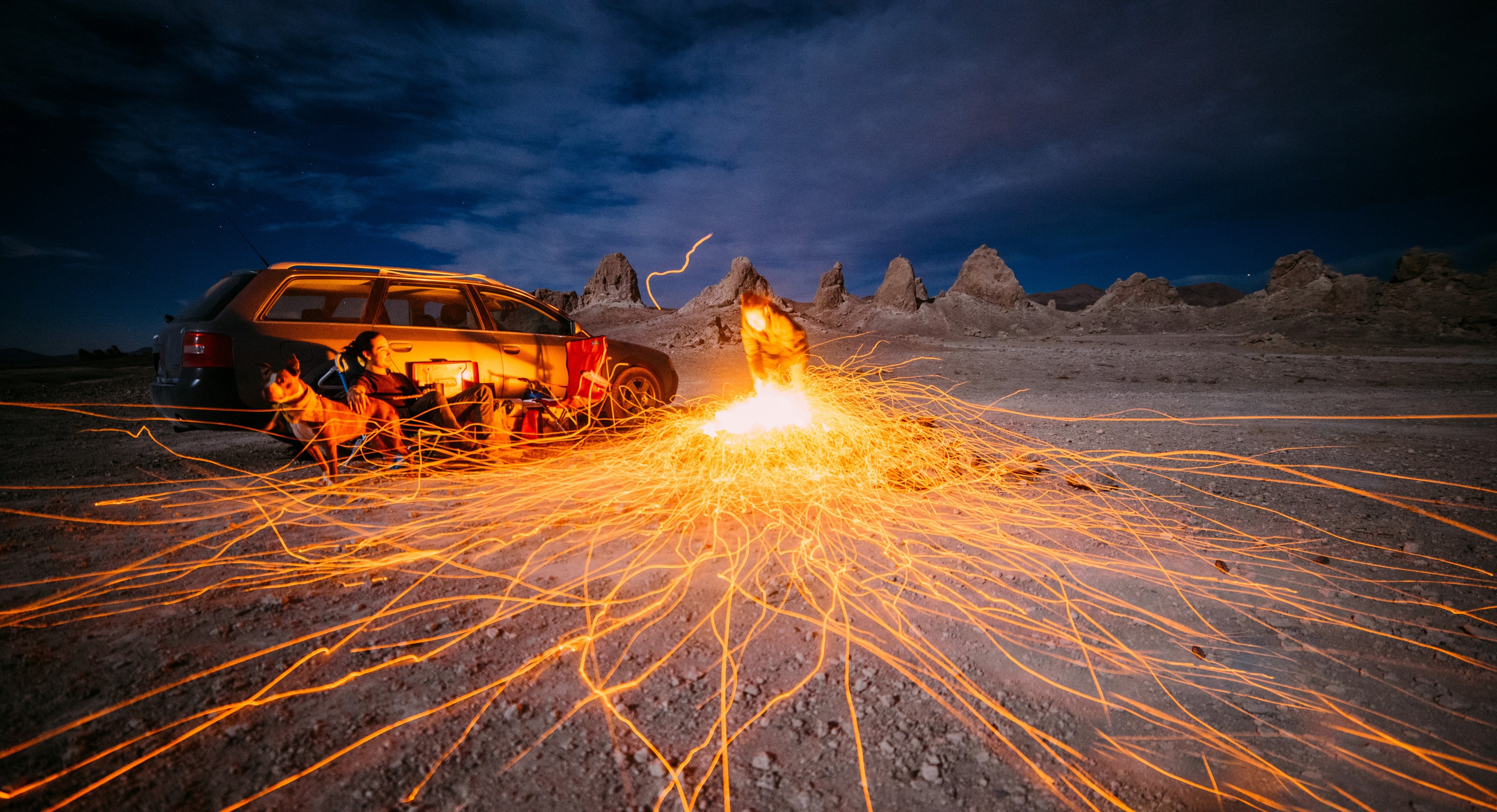 campers next to a fire at night in the desert, making the best of a windy night 4k, HD Wallpaper