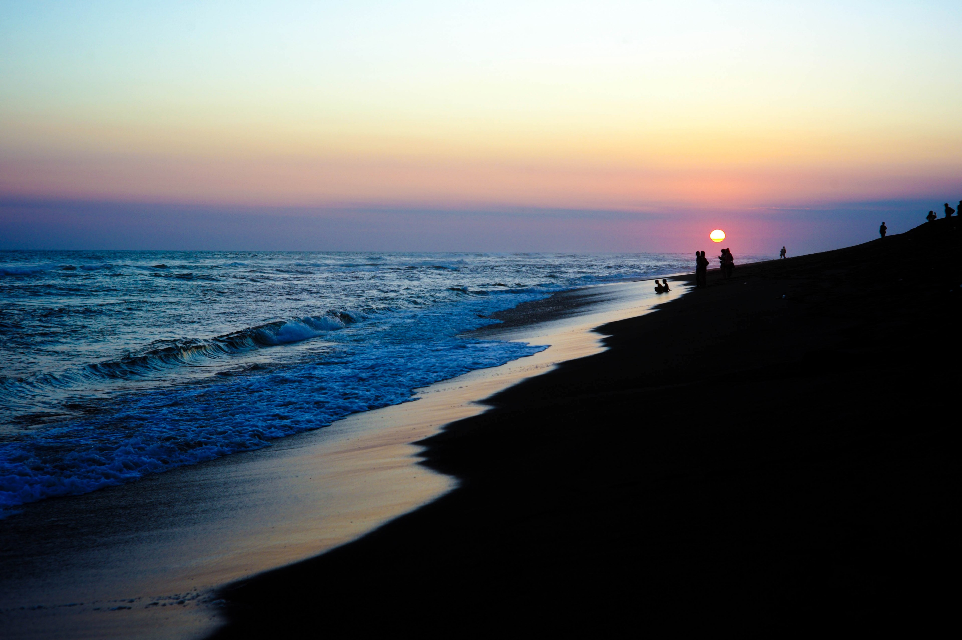 silhouetted people on the beach as the waves lap the shore while the sun sets over the coast, sunset over the beach 4k, HD Wallpaper