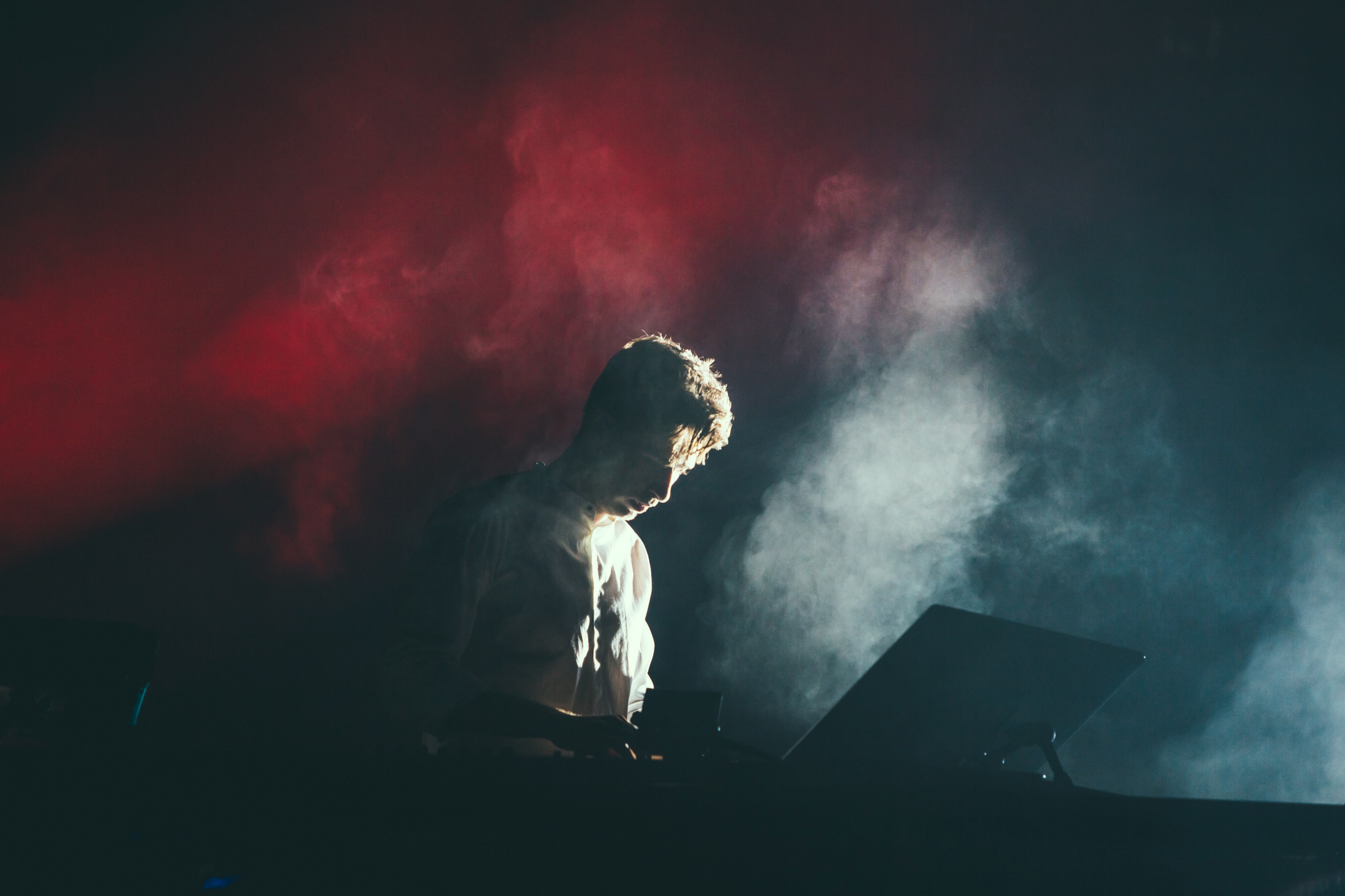a musician in a white shirt on stage with white and red lights breaking through the smoke behind his back, musician in white and red smoke 4k, HD Wallpaper