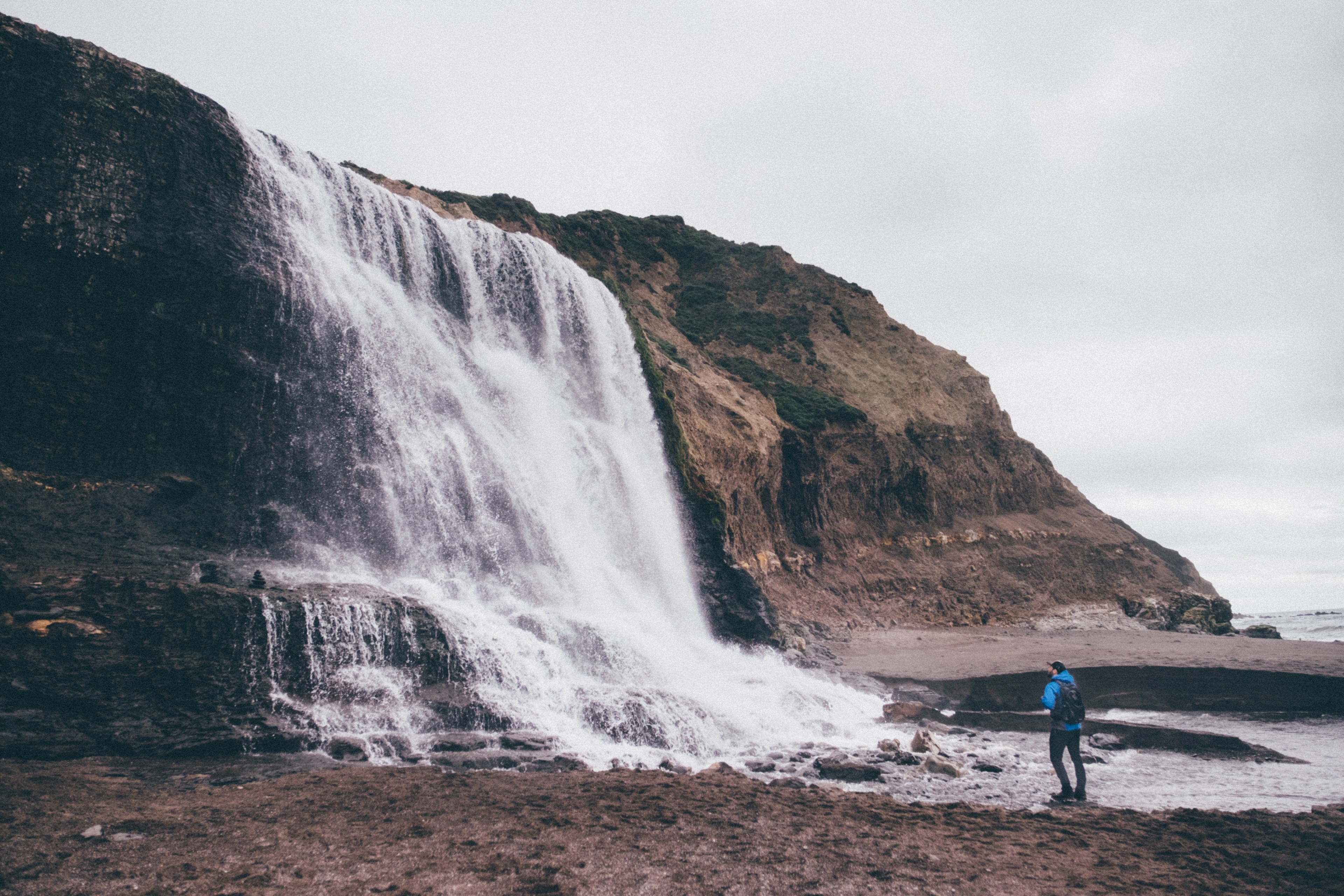 a male hiker standing near a small waterfall, in awe 4k, HD Wallpaper