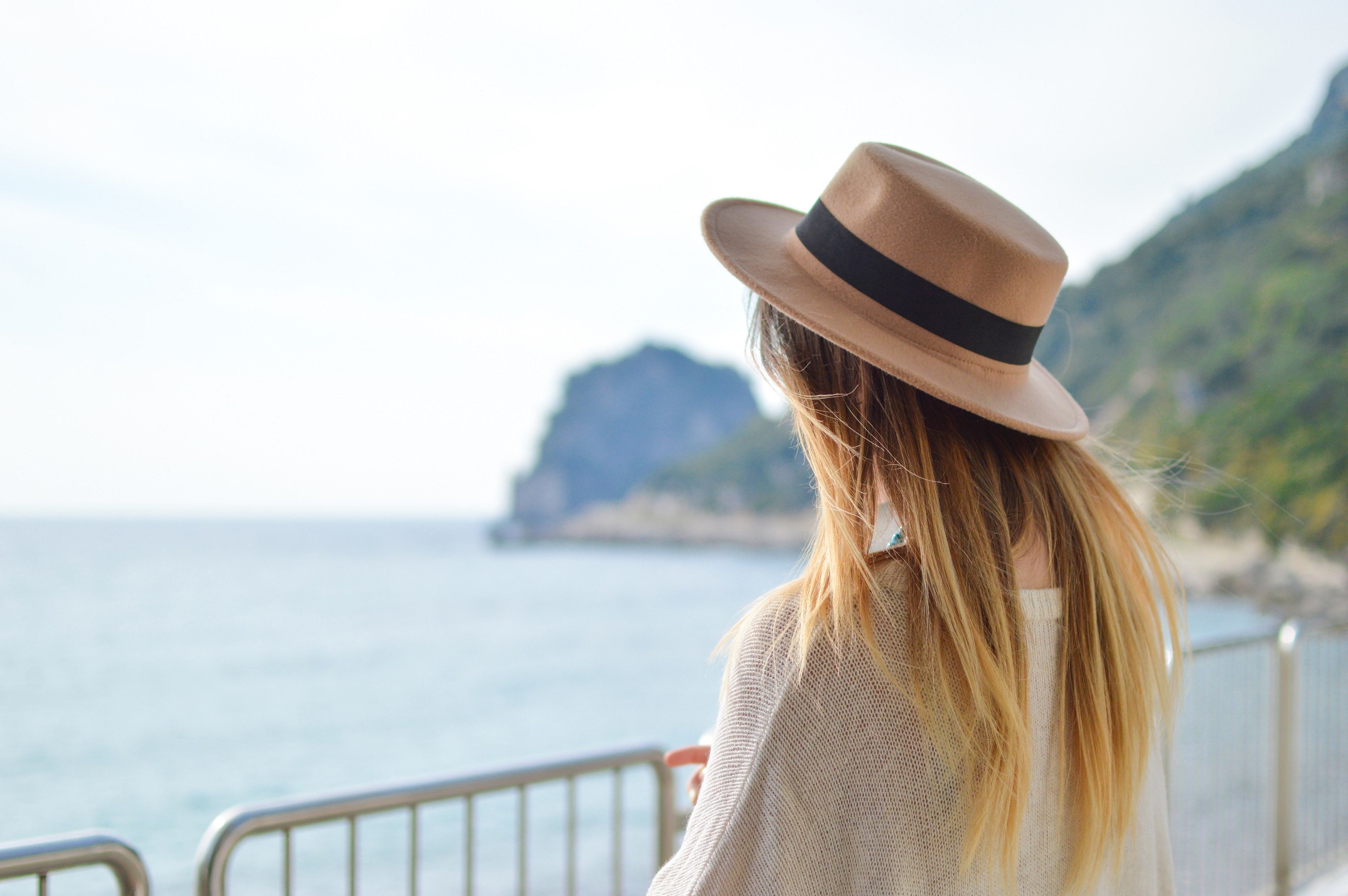 woman in a summer hat standing near a railing looking at the ocean, overlooking the ocean 4k, HD Wallpaper