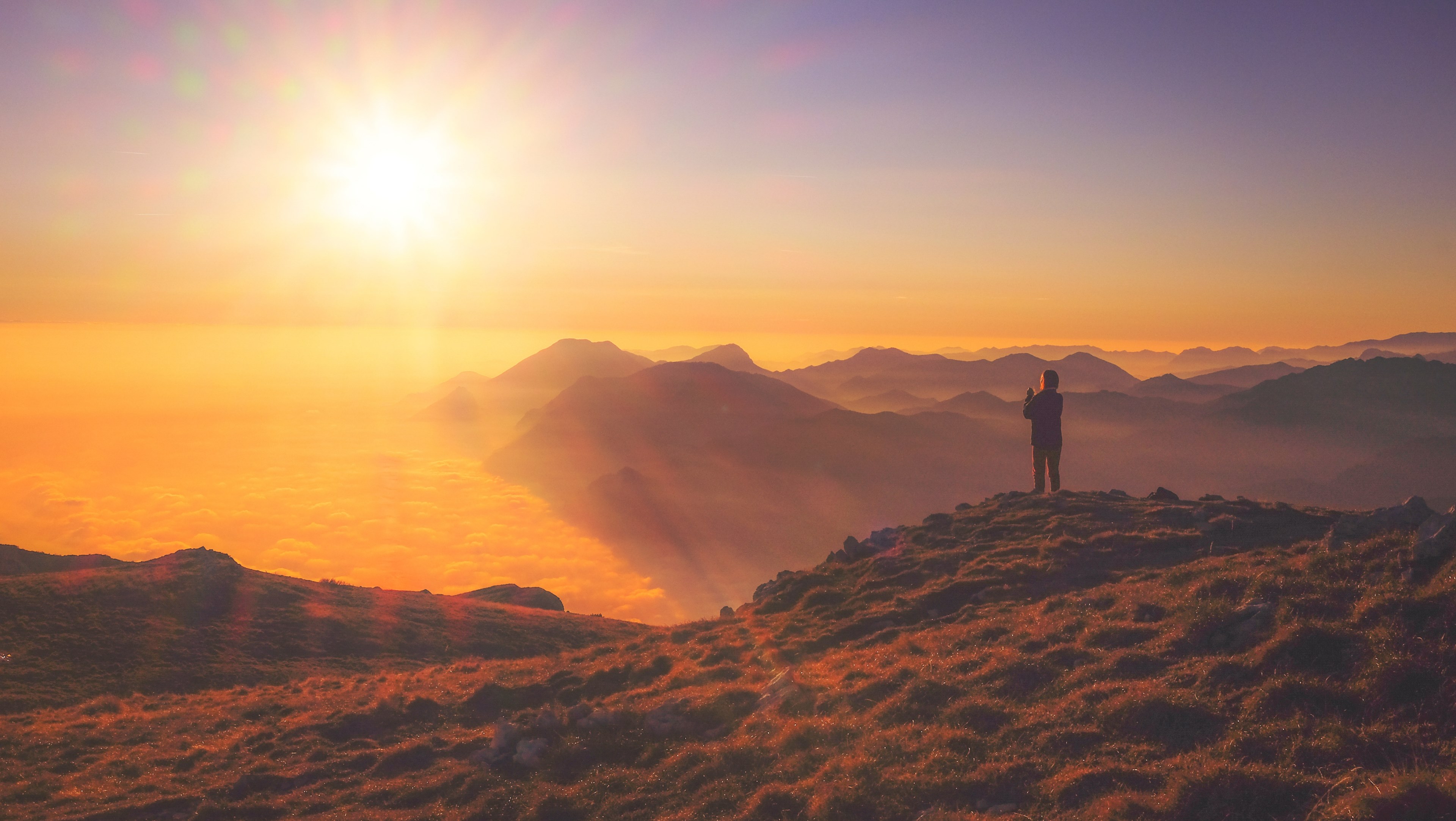 a person standing on a peak overlooking a cloudy foggy valley during sunset, cloud mountain sunset and sunrise 4k, HD Wallpaper