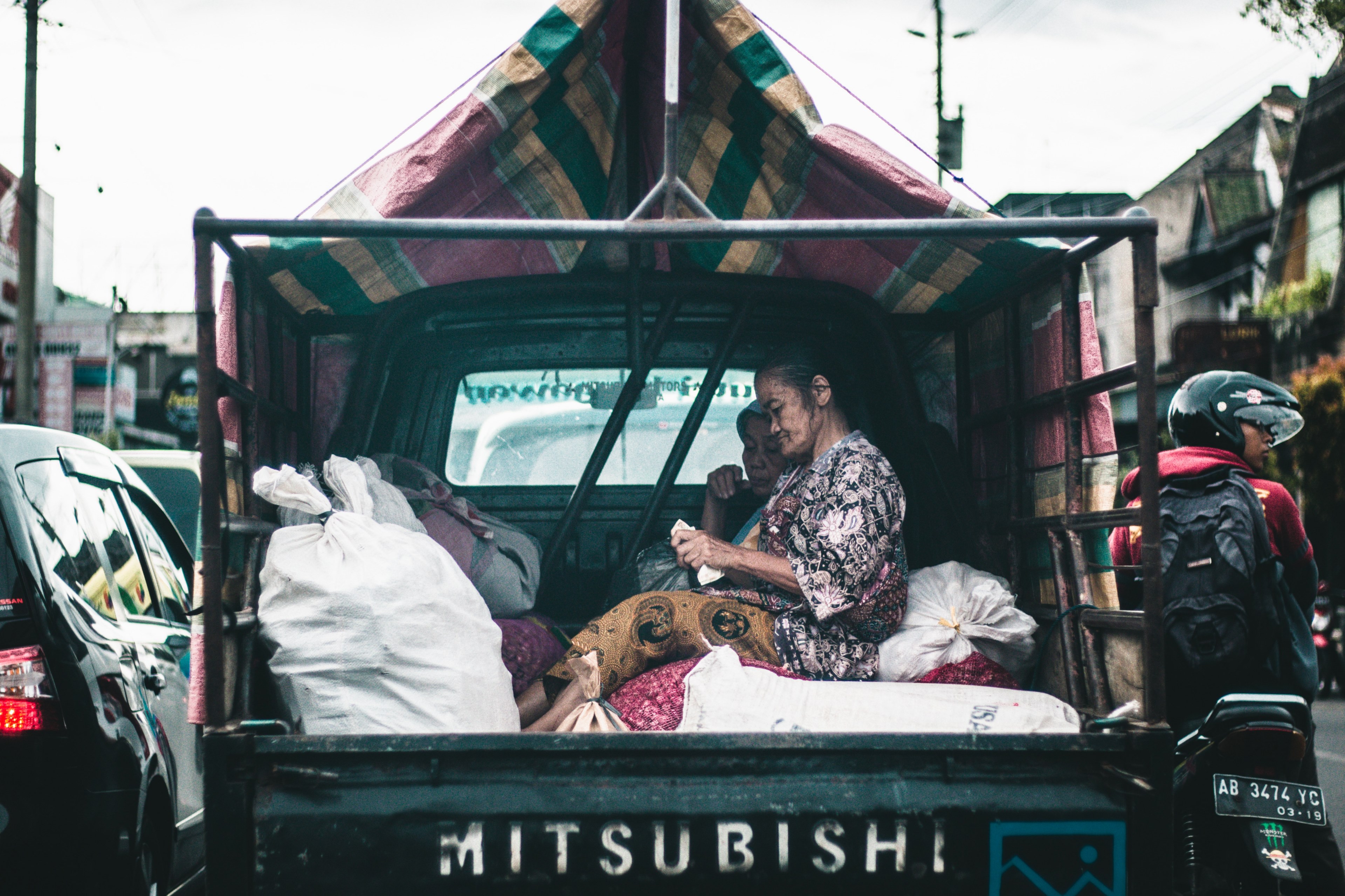 two women sit on sacks in the back of a mitsubishi truck, workers without age limit 4k, HD Wallpaper